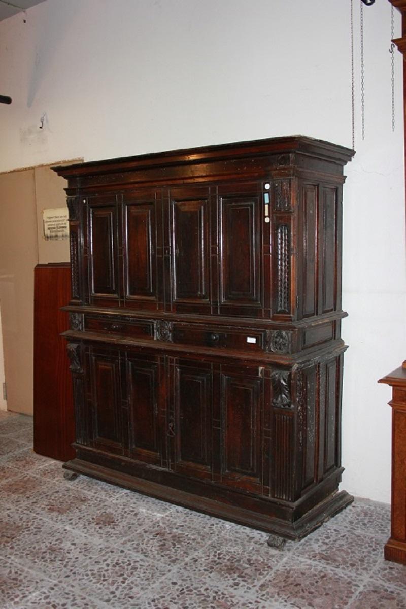 Magnificent Italian sideboard from the 1500s, Renaissance style, in walnut wood. It features an upper body with 2 closed doors, a central body with 2 drawers, and a lower body also consisting of 2 closed doors; the entire piece is adorned with