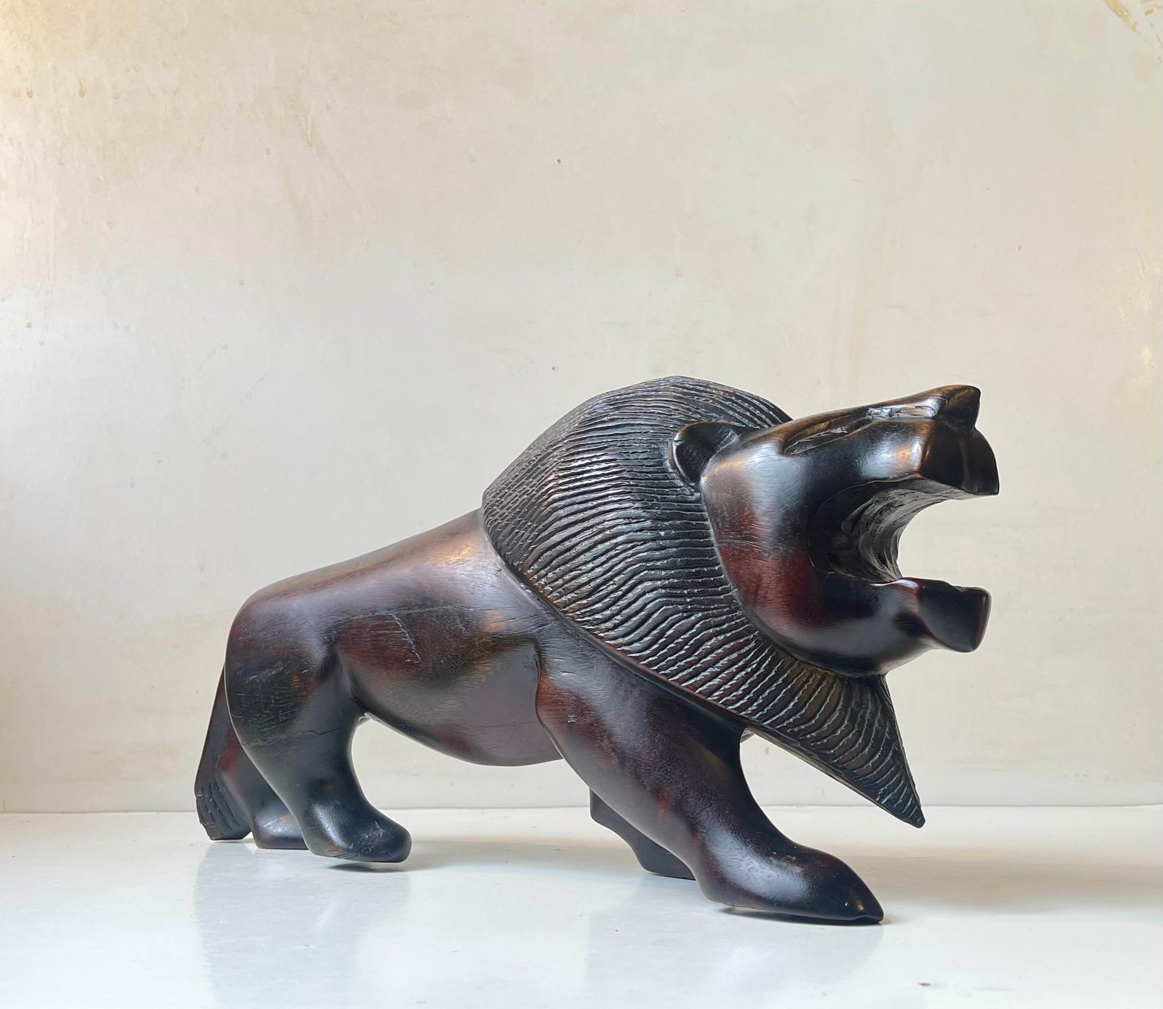 A heavy Lion sculpture in hand-carved/tooled hardwood. Stylized features very reminiscent of art deco. It is a piece unique but its origin is unclear. We suspect it was made anywhere between 1920-70. It has no markings of any kind. It has a