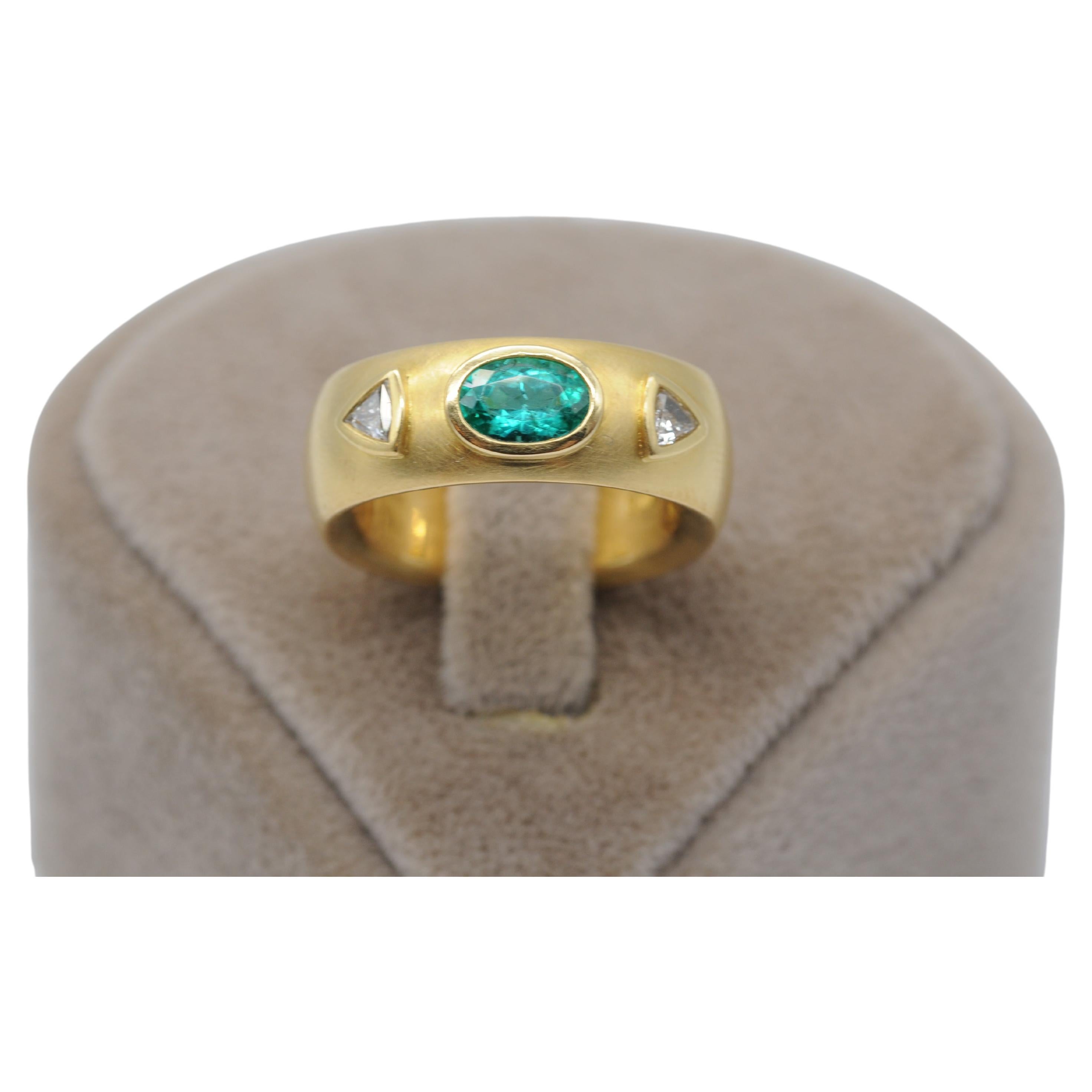 Immerse yourself in the exquisite elegance of this stunning 21.6k (900er) yellow gold ring, a true masterpiece crafted by a skilled old German goldsmith. Adorned with a resplendent oval-cut emerald at its center, flanked by dazzling triangle-cut