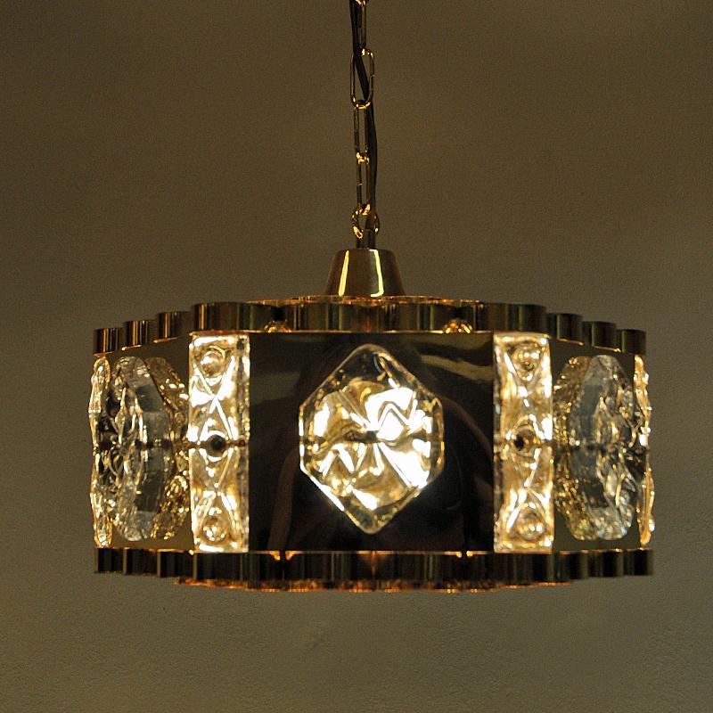 Glamouros and stunning vintage ceiling chandelier by AS Metall Service, Norway 1970s. Decorated with brass and brilliant cut clear six edged stars glass decors. Cylindershaped brass circles on top and bottom of the lamp. The lamp gives a sculptural