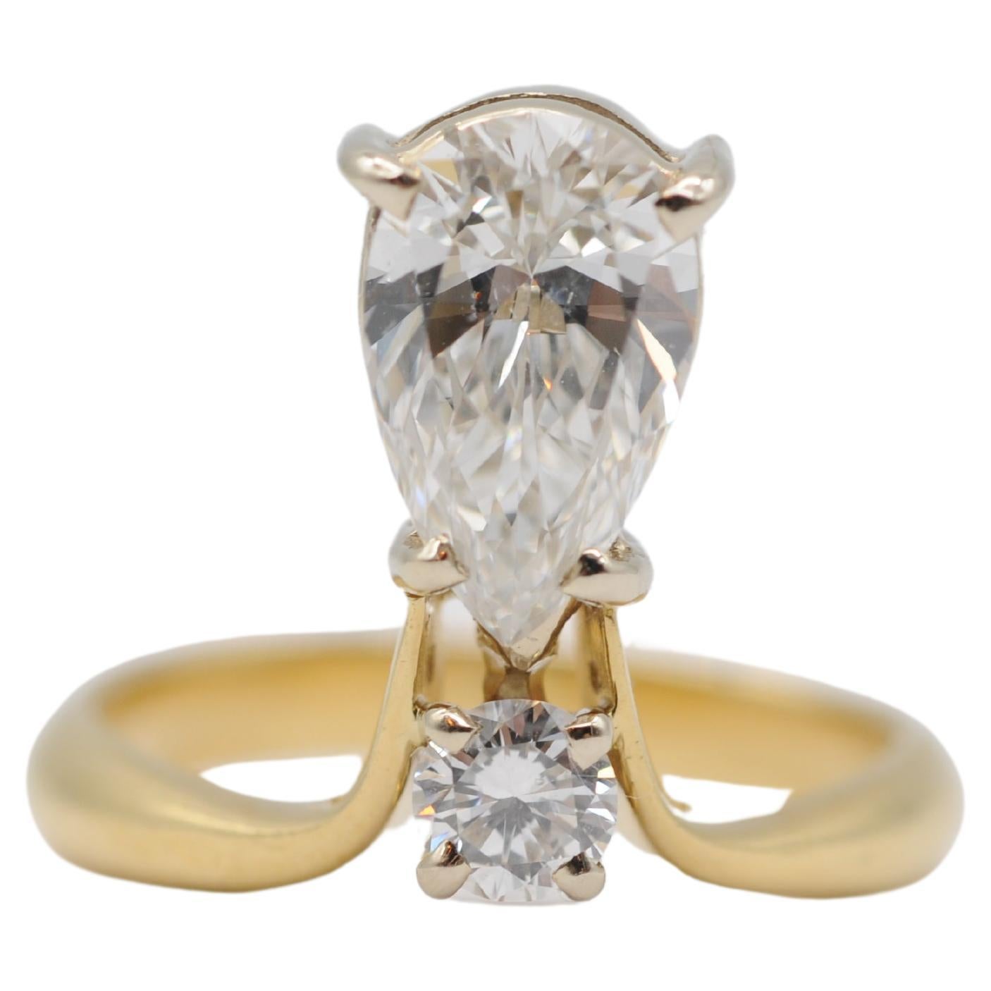 Behold the enchanting beauty of this magnificent 18k yellow gold ring, adorned with exquisite gemstones that captivate the eye. At its center sits a stunning pear-cut diamond, its brilliance unmatched as it catches the light and dances with every