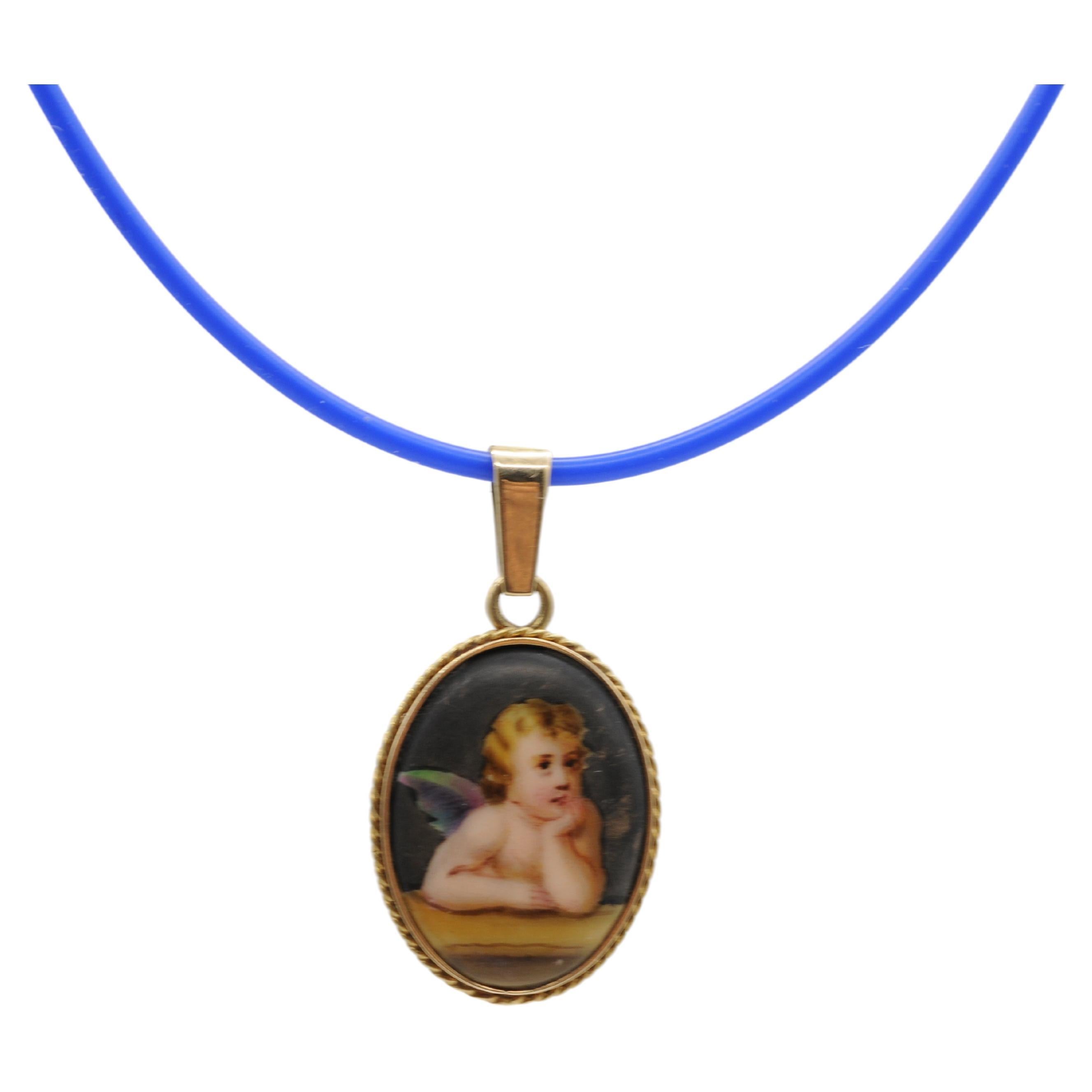 Behold this exquisite pendant, a masterpiece crafted from 14k yellow gold, adorned with a delicate porcelain plate. Hand-painted with intricate detail, it depicts a contemplative cherub, evoking a sense of serenity and introspection. The