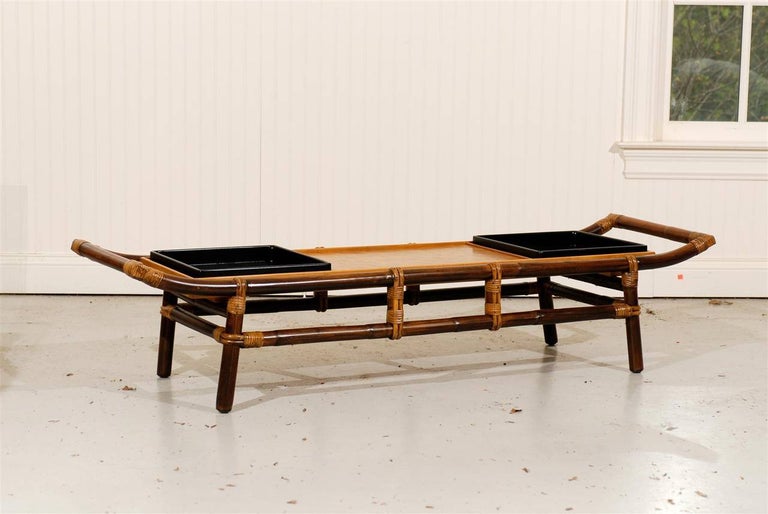 An exquisite meticulously restored Pagoda form coffee table or bench. Stout expertly constructed rattan frame with a beautiful woven raffia top which produces a fabulous parquet effect. A slick pair of black lacquer trays accent the top. Beautifully
