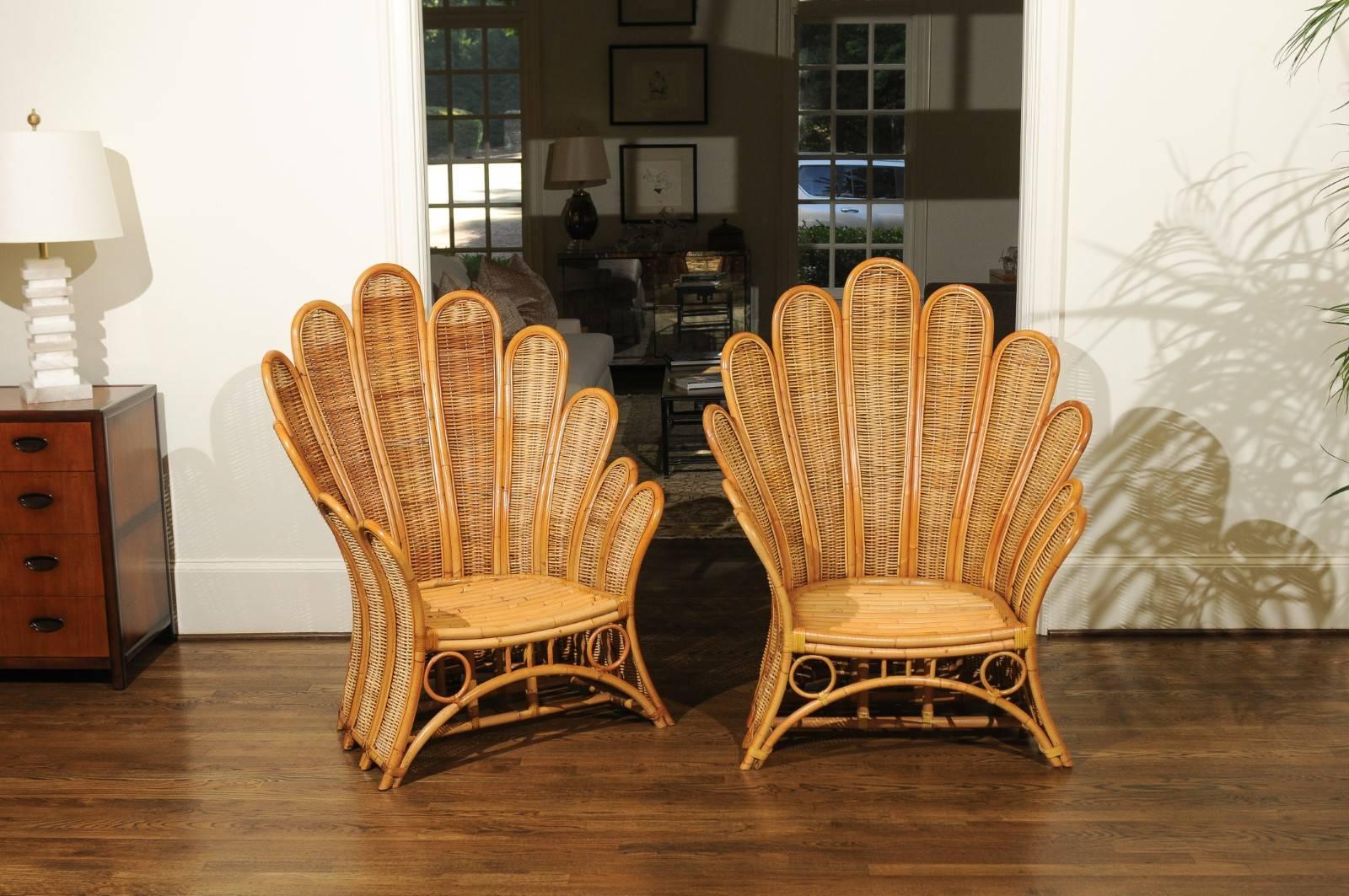 A staggering pair of large-scale club chairs, circa 1980. Beautifully conceived and expertly constructed rattan and wicker frame which captures the feel of Palm leaves; handsome leather binding accents. Important pieces that will establish the tone