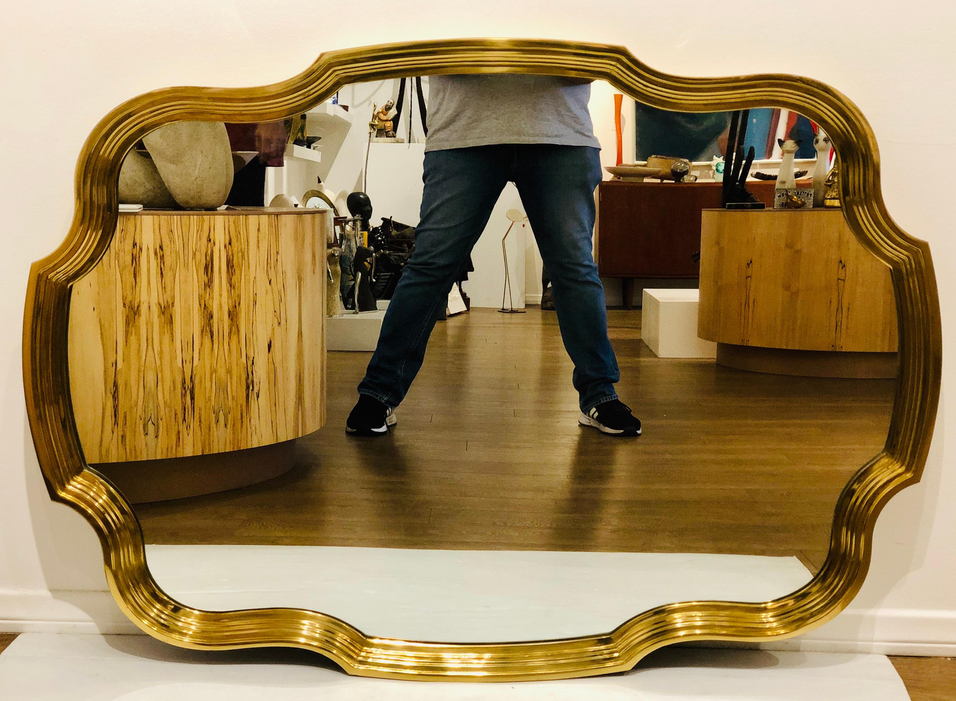 A one of a kind solid scalloped polished brass mirror by Baker furniture. This piece has been polished and the mirror was replace, you can hang it horizontal or vertical in excellent condition, circa 1950s.