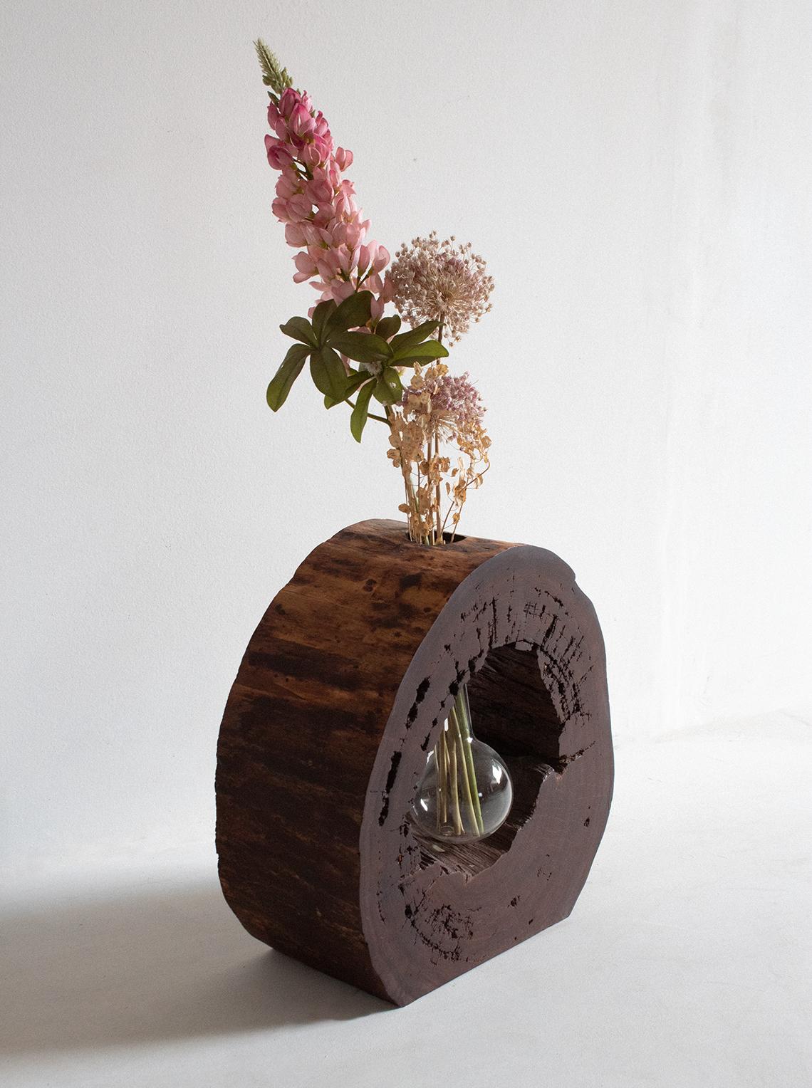 Introducing our exquisite hand-carved vase, crafted from a slice of a stem of Mexican Granadillo wood. This stunning piece showcases the rich, deep hues and intricate grain patterns characteristic of Granadillo wood, making it a true work of