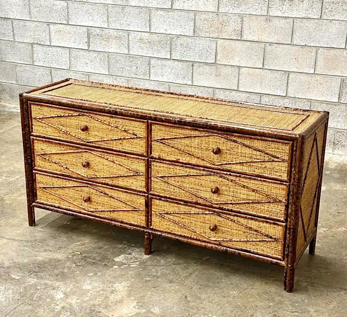A stellar restored British Colonial style six-drawer Organic commode circa, 1980. Expertly crafted mahogany case construction veneered in cane raffia. Handsome case accents in a burnished faux-bamboo finish, which creates a wonderful Tortoiseshell