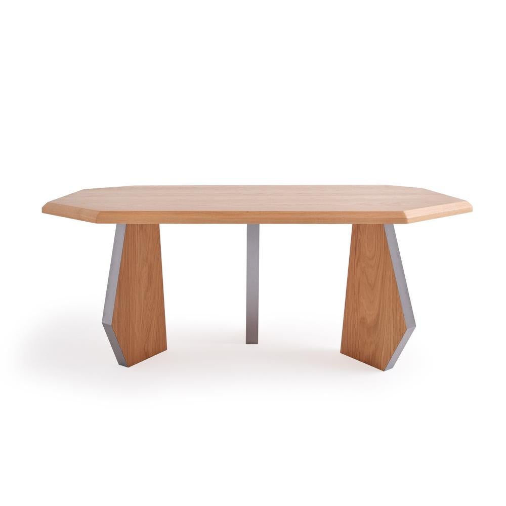 The dining table is handmade by applying silk matte varnish on oak. One side of each of its three legs is covered with metal material.