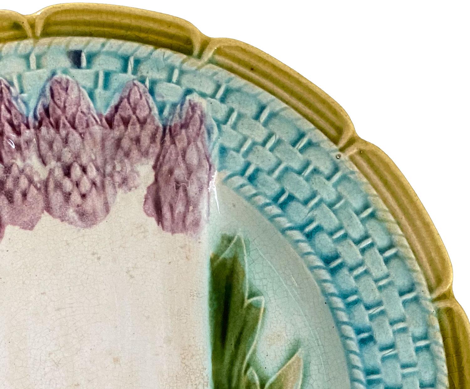 Cette assiette en majolique peinte à la main en forme d'asperge a été fabriquée en France au XIXe siècle. Assiette à asperges en Barbotine - barbotine décorée d'asperges colorées dans la partie centrale, d'une texture en osier sur la lèvre et d'un