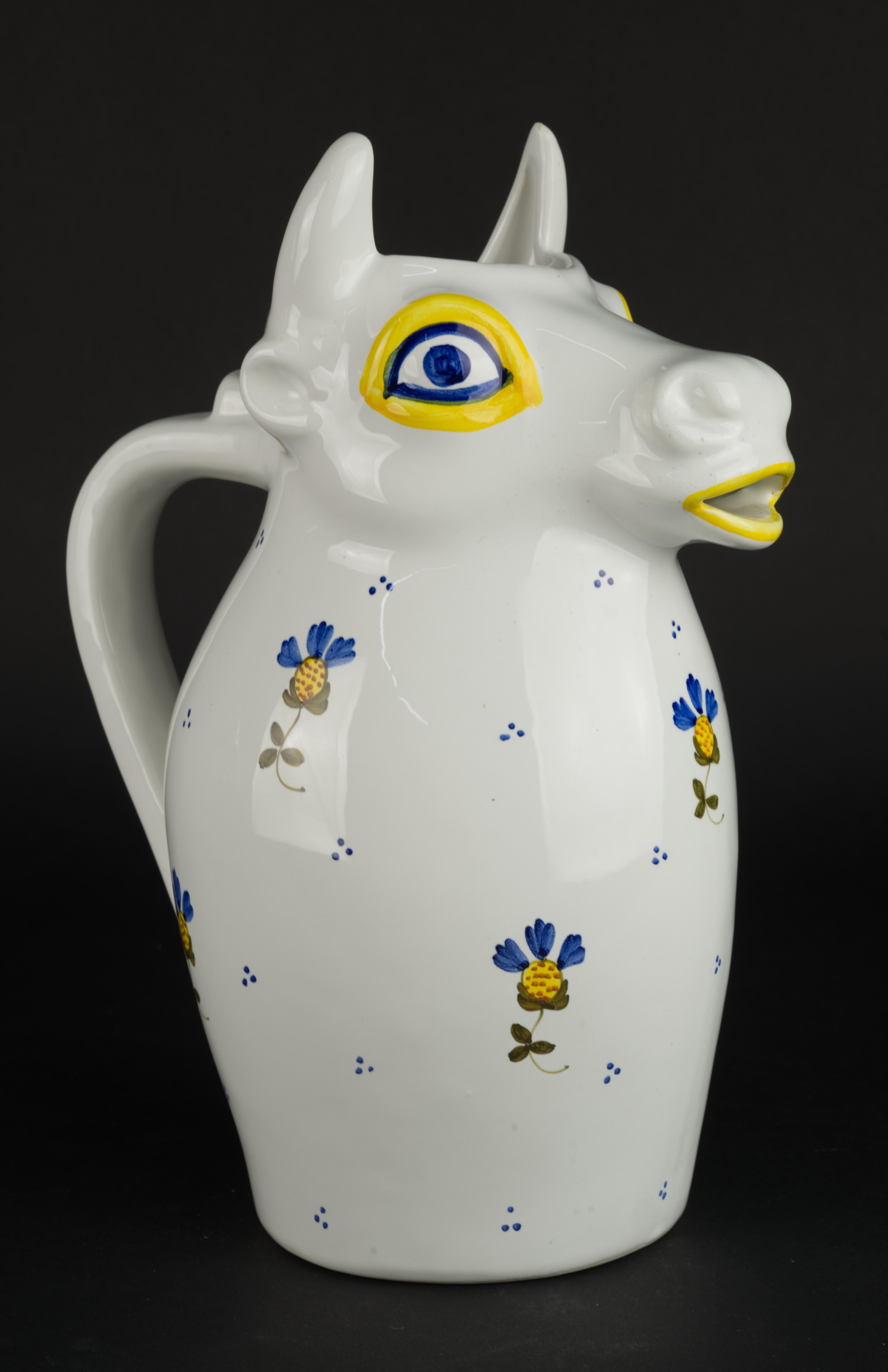  Unusual and playful majolica pitcher has its top part shaped in form of a bull's head with bull's mouth forming the spout. It is decorated with hand painted traditional Italian flower designs in blue and yellow and blue dots on bright white glaze.