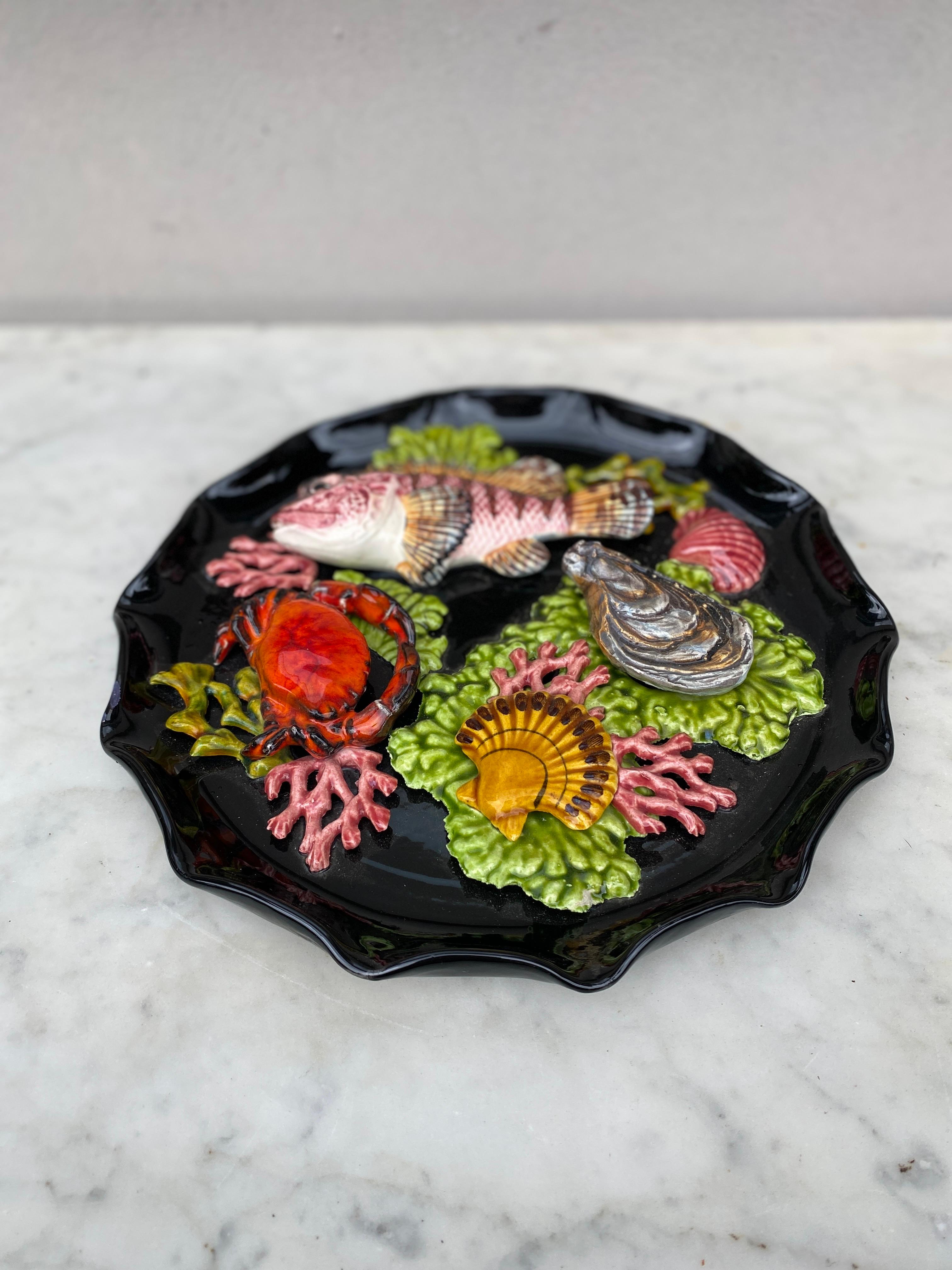 Majolica sealife platter Vallauris, circa 1950.
High relief of 2 fishs, seaweeds, shells, crab, oyster.
Nautical style.
10 inches diameter 
 