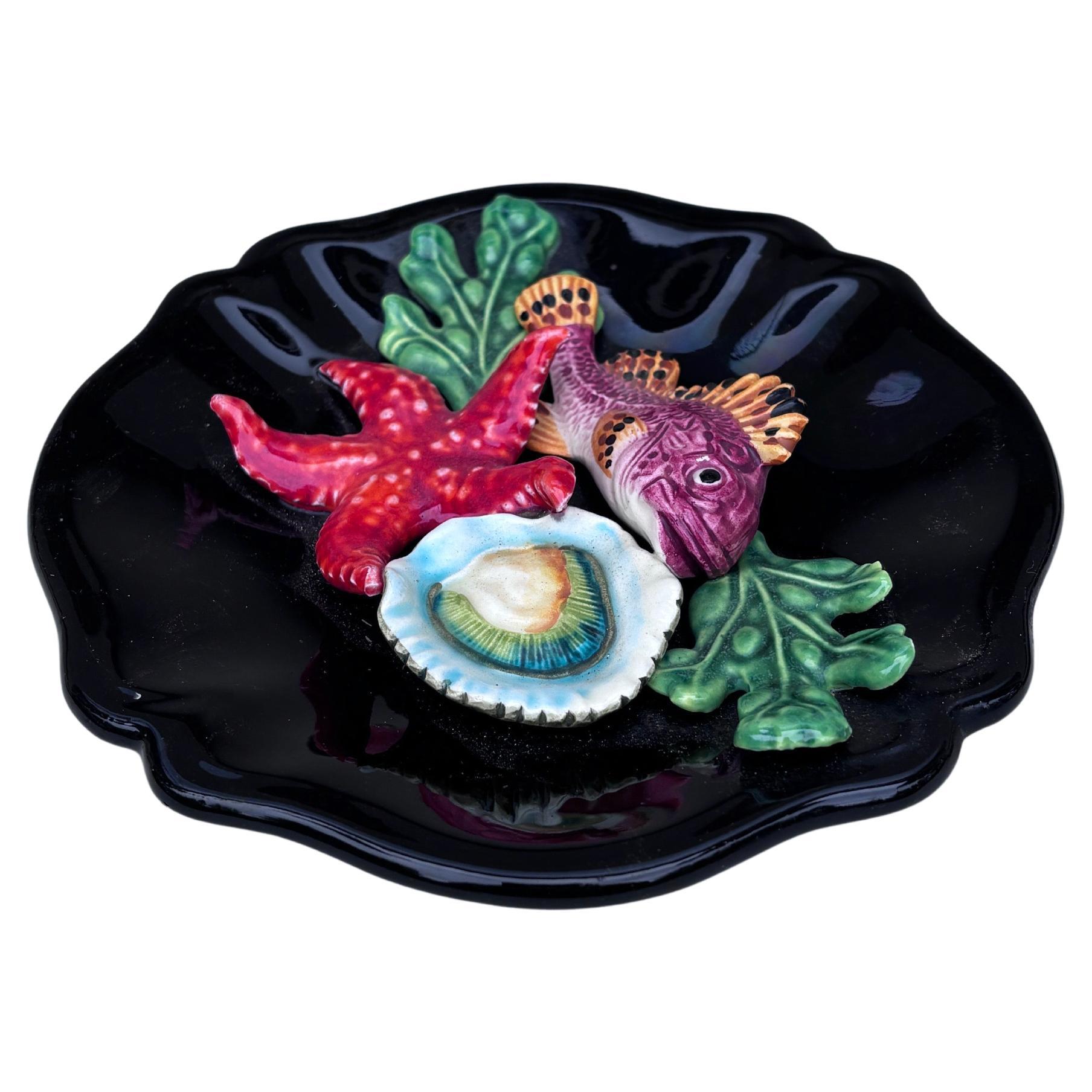 Plato de mayólica Vallauris, hacia 1950.
Altorrelieve de un pez, algas, estrella de mar y ostra.
Estilo náutico.
7,3 pulgadas de diámetro 
 