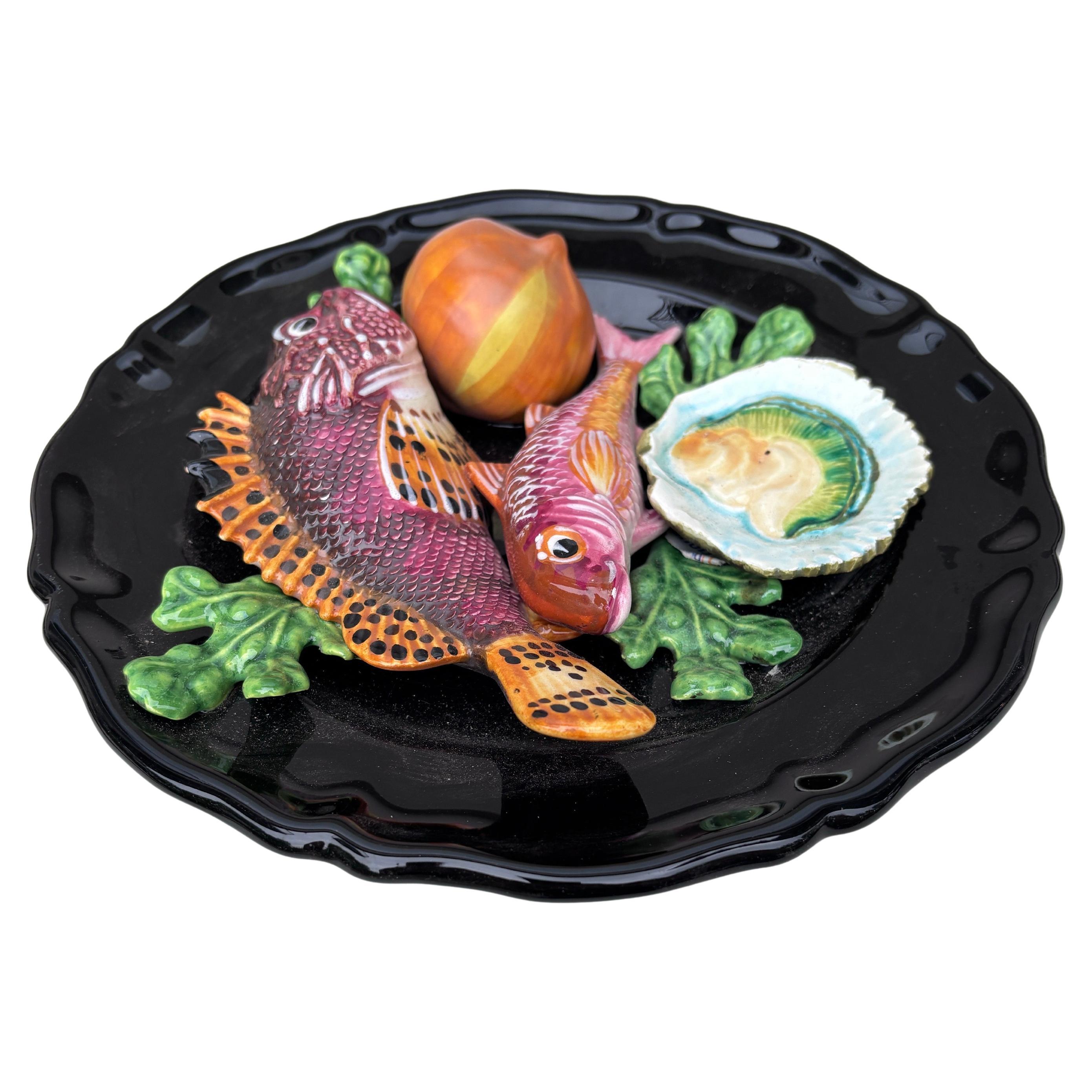 Plato de mayólica Vallauris, hacia 1950.
Altorrelieve de 2 peces, algas, conchas, cebolla , ostra.
Estilo náutico.
10 pulgadas de diámetro 
 