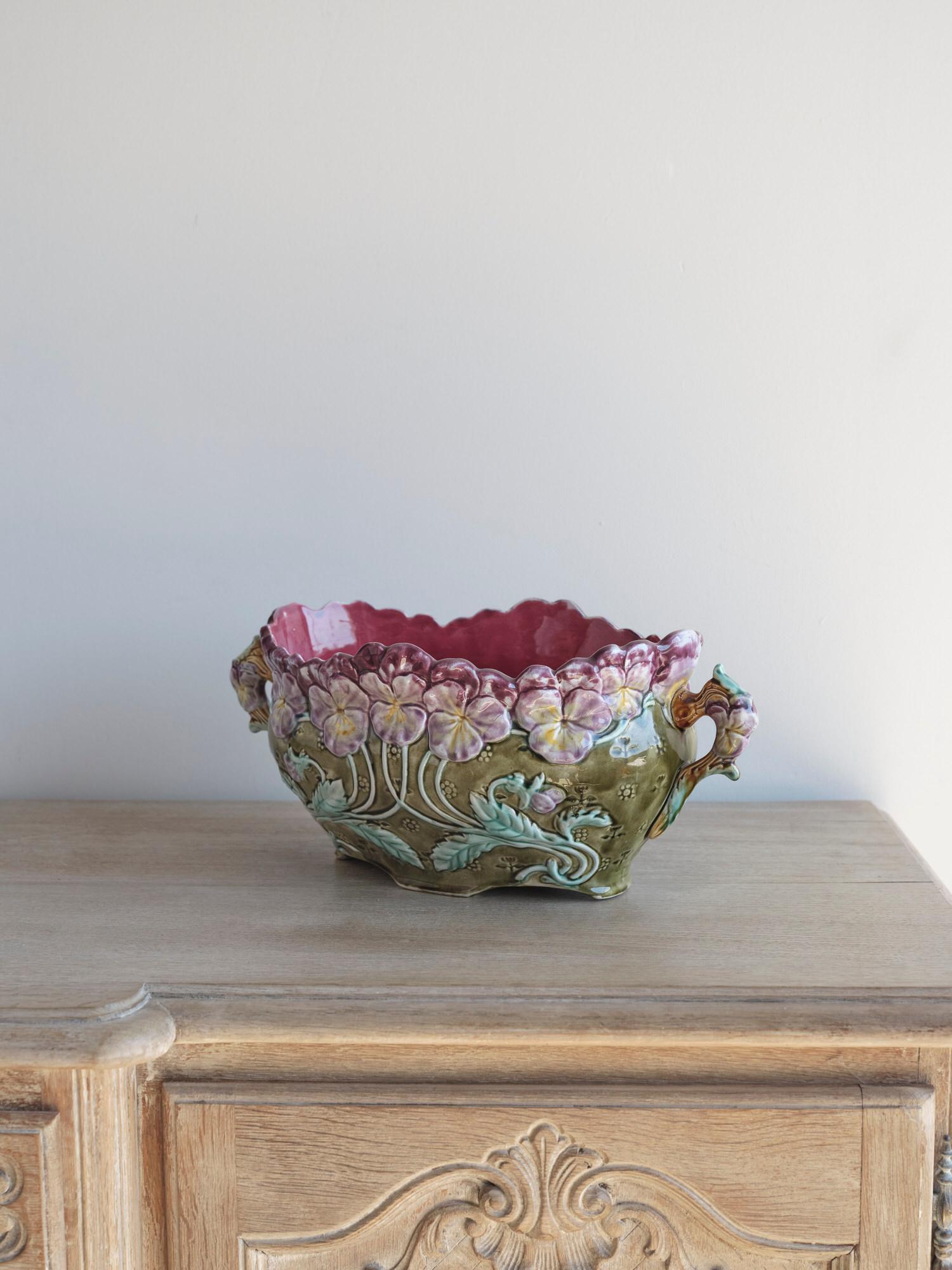 This beautiful French Majolica flower planter, circa 1900, has so many lovely details and vibrant colors. The dominating colors are purple and green. There are several purple flowers with a green background color. The interior of the bowl is a light