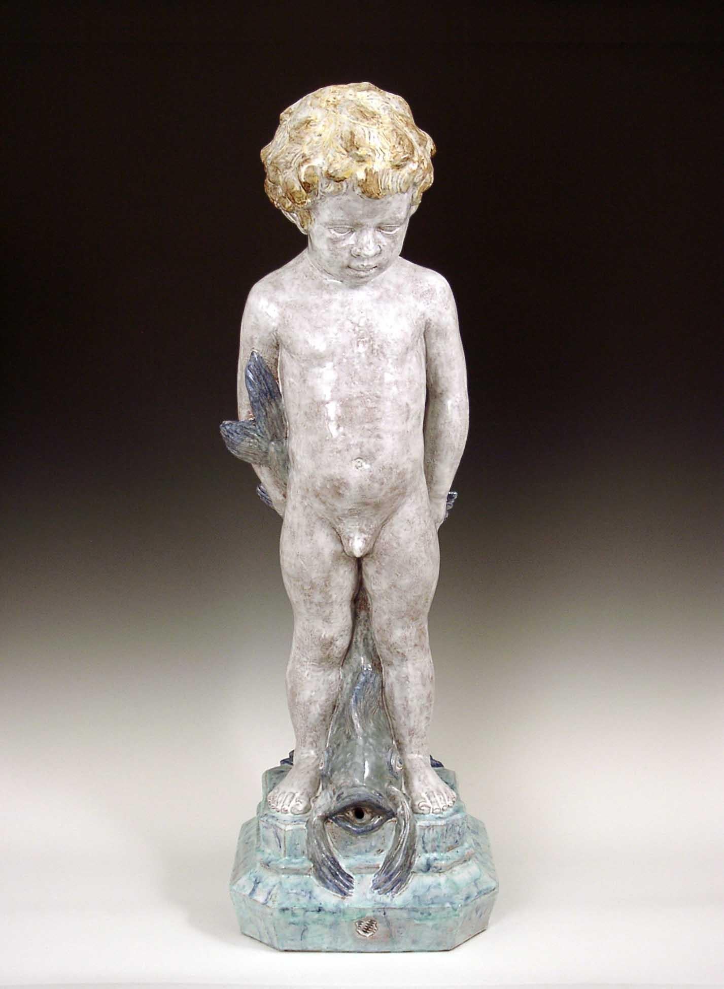 Diese handgefertigte und handbemalte Majolika-Figur eines Jungen mit einem Fisch wird in den Ateliers der Nymphenburger Porzellanmanufaktur in München, Deutschland, hergestellt. Sie stellen handgefertigte Figuren in Majolika-Technik her, die Ihren