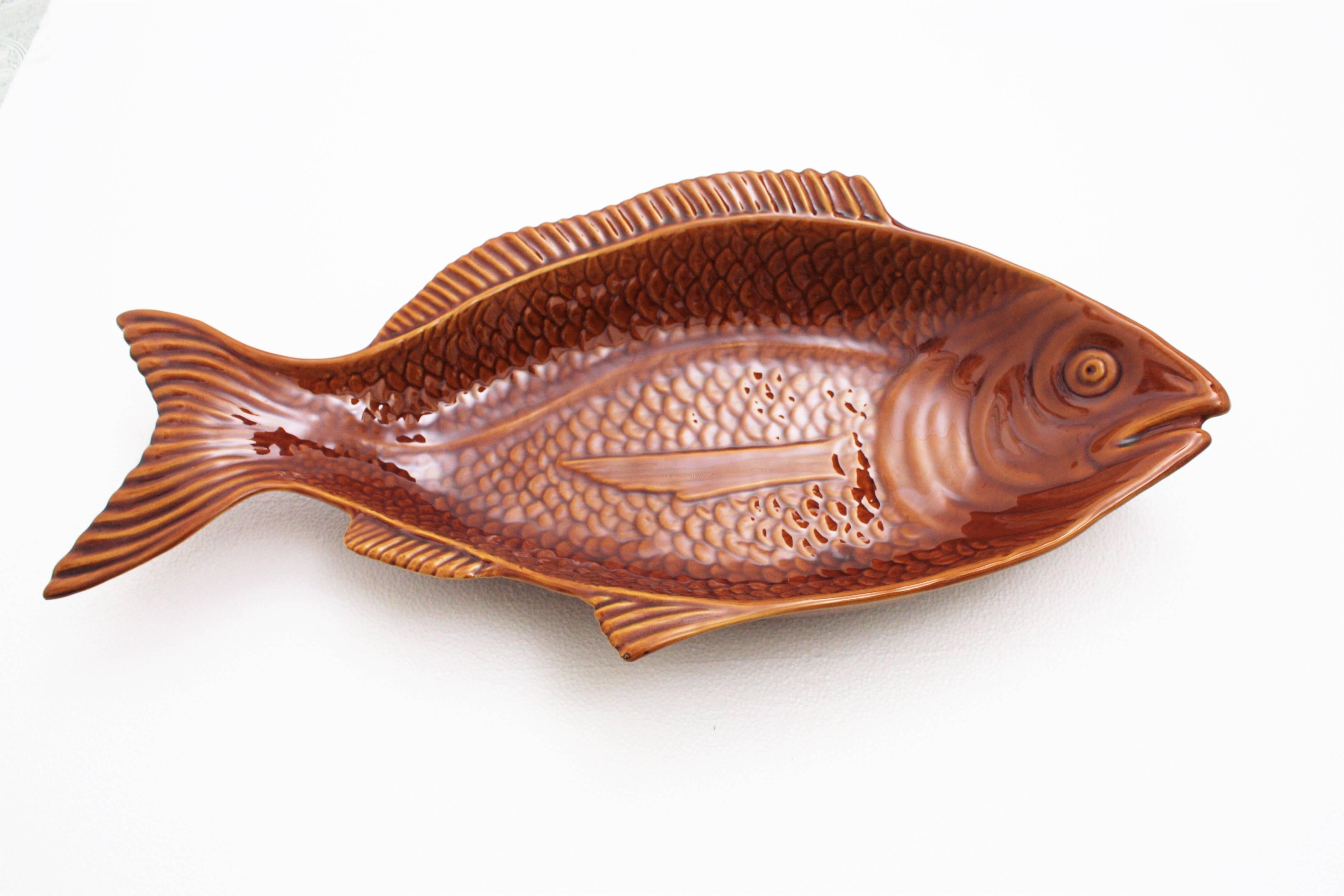 A glazed ceramic large fish platter in brown and toffee colors manufactured by Secla ceramics factory. Portugal, 1960s.
A very interesting piece due to its very large size.
Useful as serving platter, centerpiece but also lovely to use it to