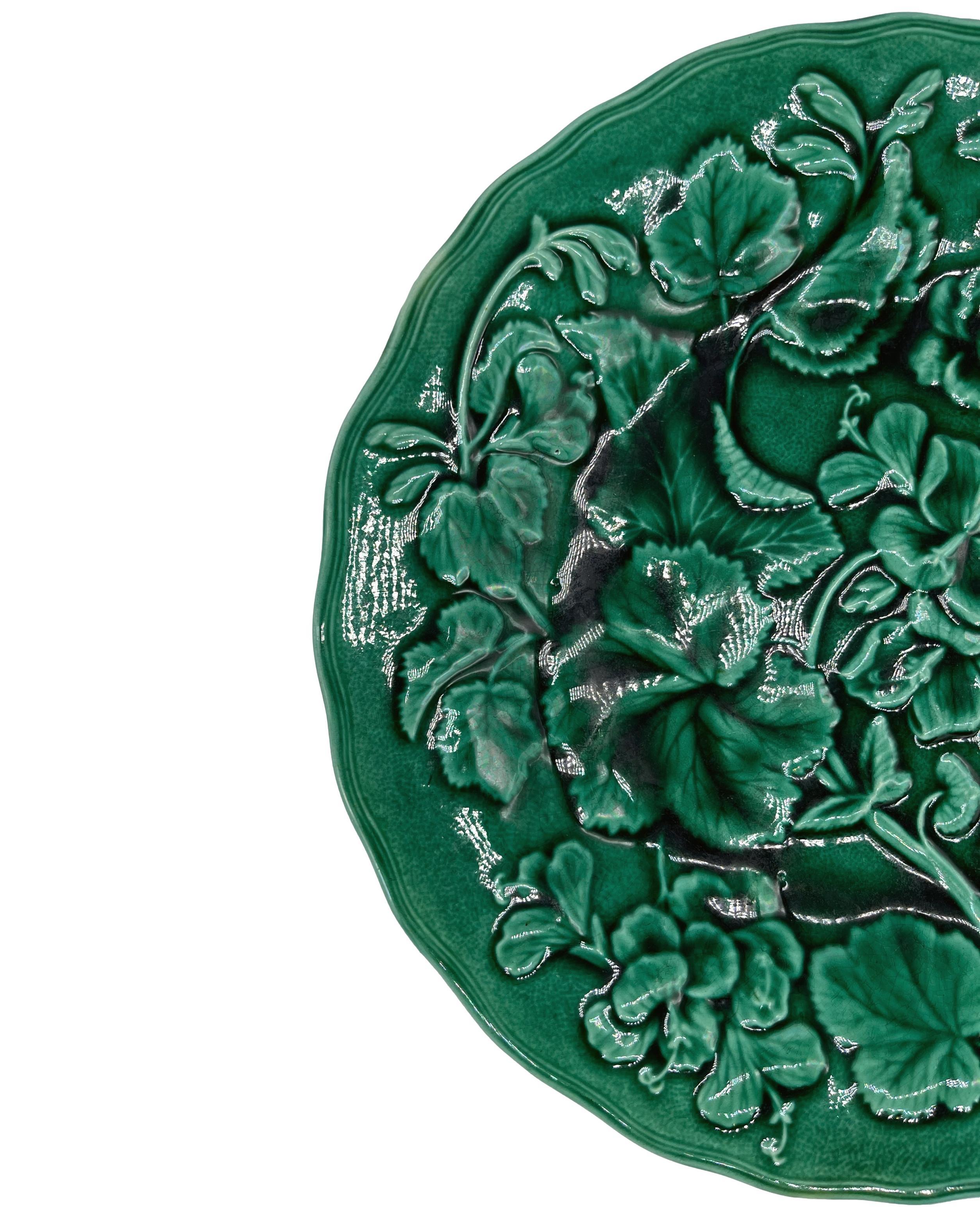 English majolica green-glazed 9.13-inch plate, with relief molded geranium plants and blossoms, with a shaped rim; the reverse with impressed mark: HOPE & CARTER, BURSLEM. 
For thirty years we have been among the preeminent specialists in fine