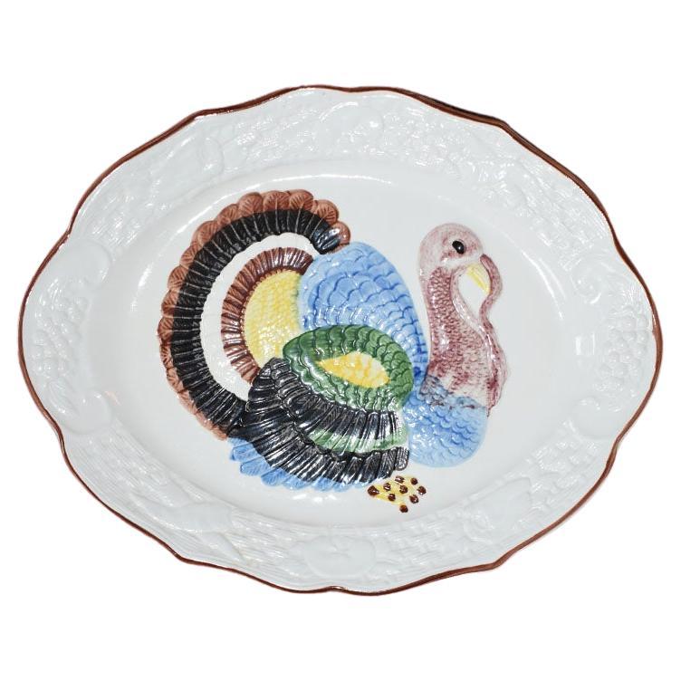 A large oval Thanksgiving turkey serving platter. Created from ceramic, this large majolica platter will be a fabulous way to add a festive touch to your holiday table. The center of the tray features a turkey in brown with colorful feathers. Around