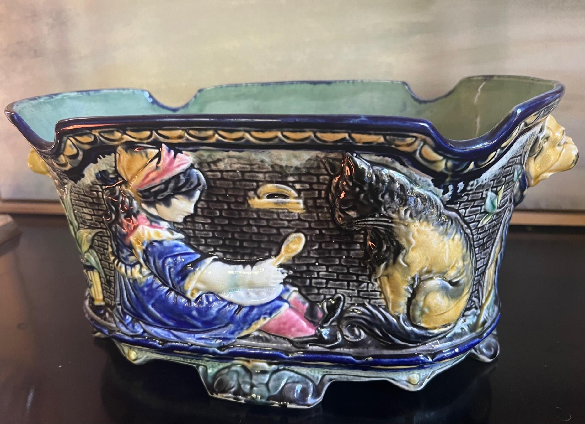 Antique majolica jardiniere made in Belgium by Wasmuel in the late 19th century. I've never seen another jardiniere like this one with dogs on each side, a black brick background and children playing on the front with a lion and a dog. The piece has