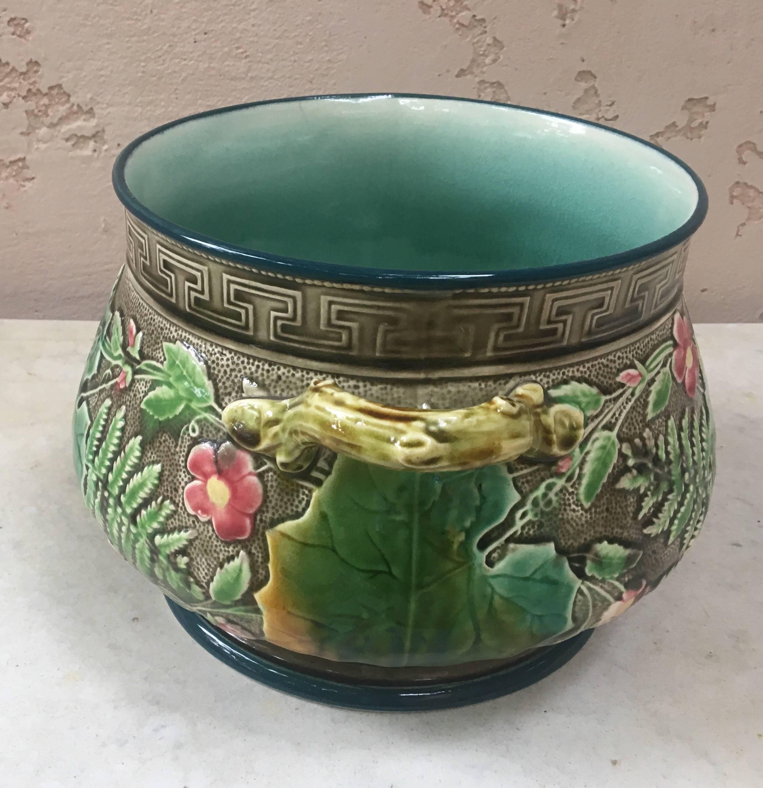 Naturalistic Majolica handled cache pot decorated with leaves, fern, pink flowers on a grey background circa 1880 signed Hippolyte Boulenger Choisy-le-Roi.
A grey key border on the top of the jardinière.
 