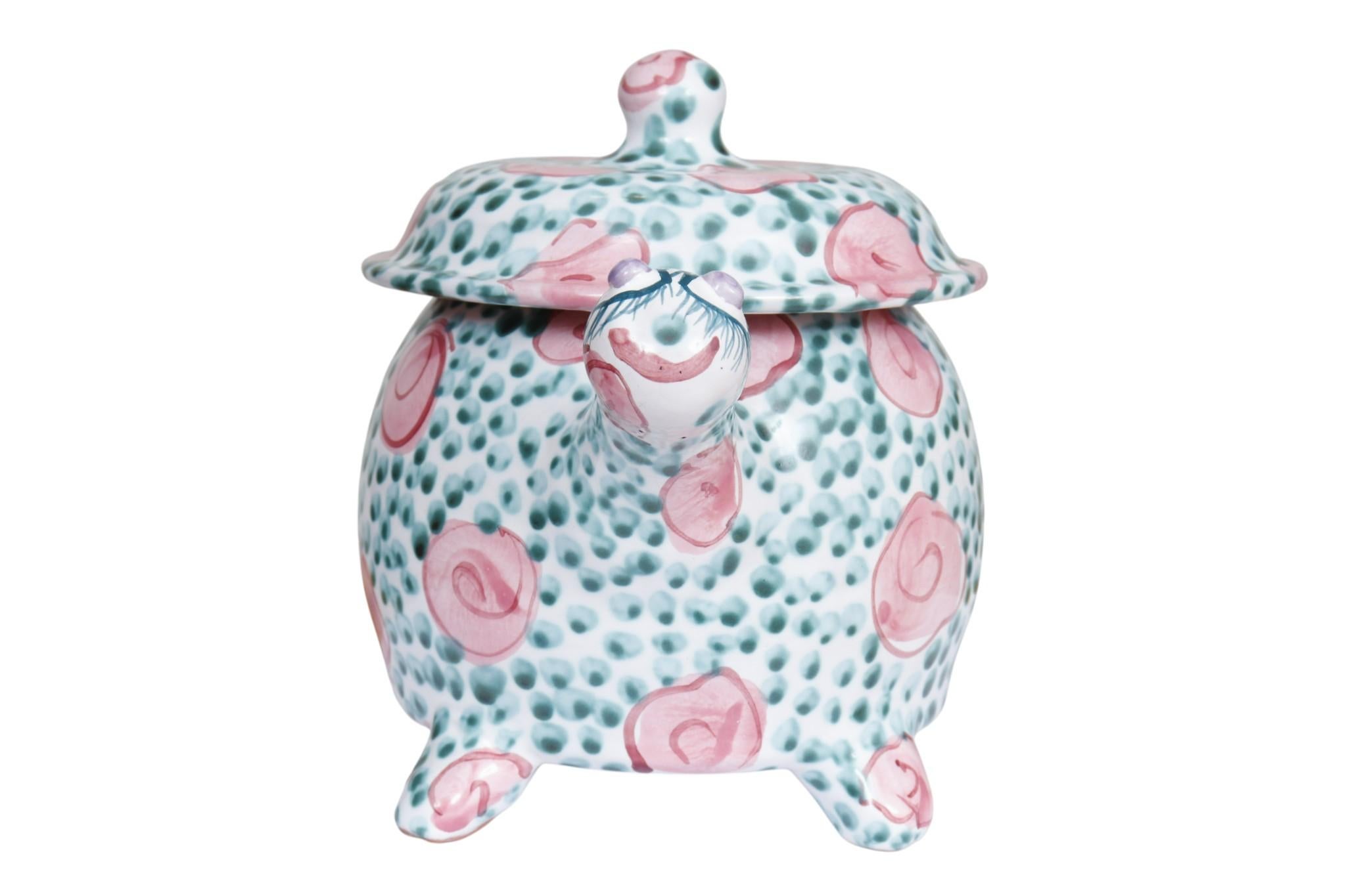 Un vaso con coperchio in maiolica del 1993 a forma di tartaruga, realizzato dal ceramista Jan Pugh. Realizzata in terracotta, la giara è dipinta e smaltata a mano con un semplice motivo di rose rosa punteggiate di fogliame verde su una base bianca.