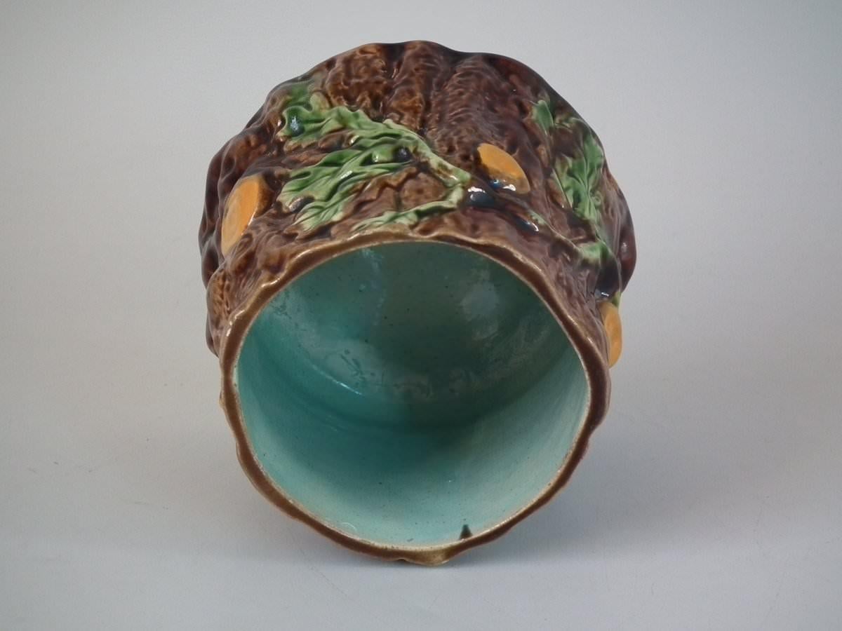 Majolica pot and cover which features oak leaves and acorns on a bark ground. Coloration: brown, green, ochre, are predominant.
