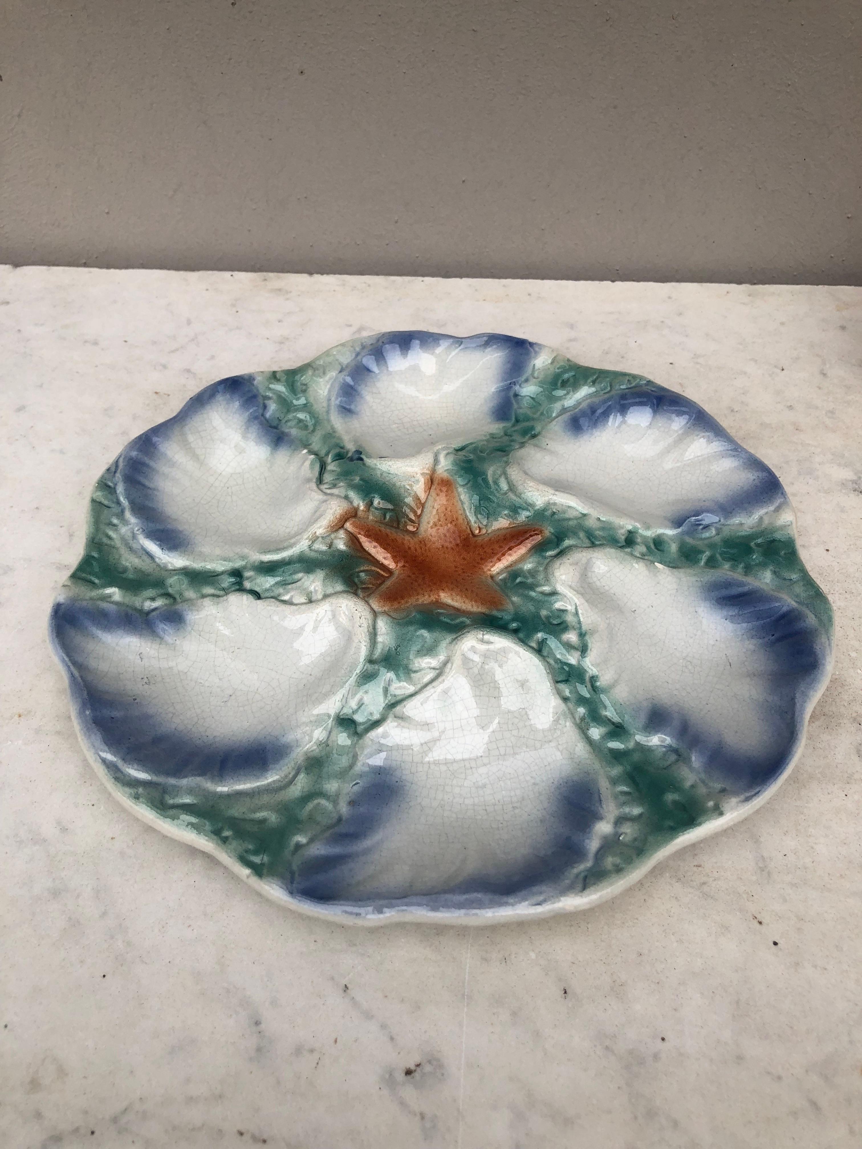 Majolica plate with orange starfish with six wells blue and white surrounded by green seaweeds signed Digoin (East of France), circa 1900.