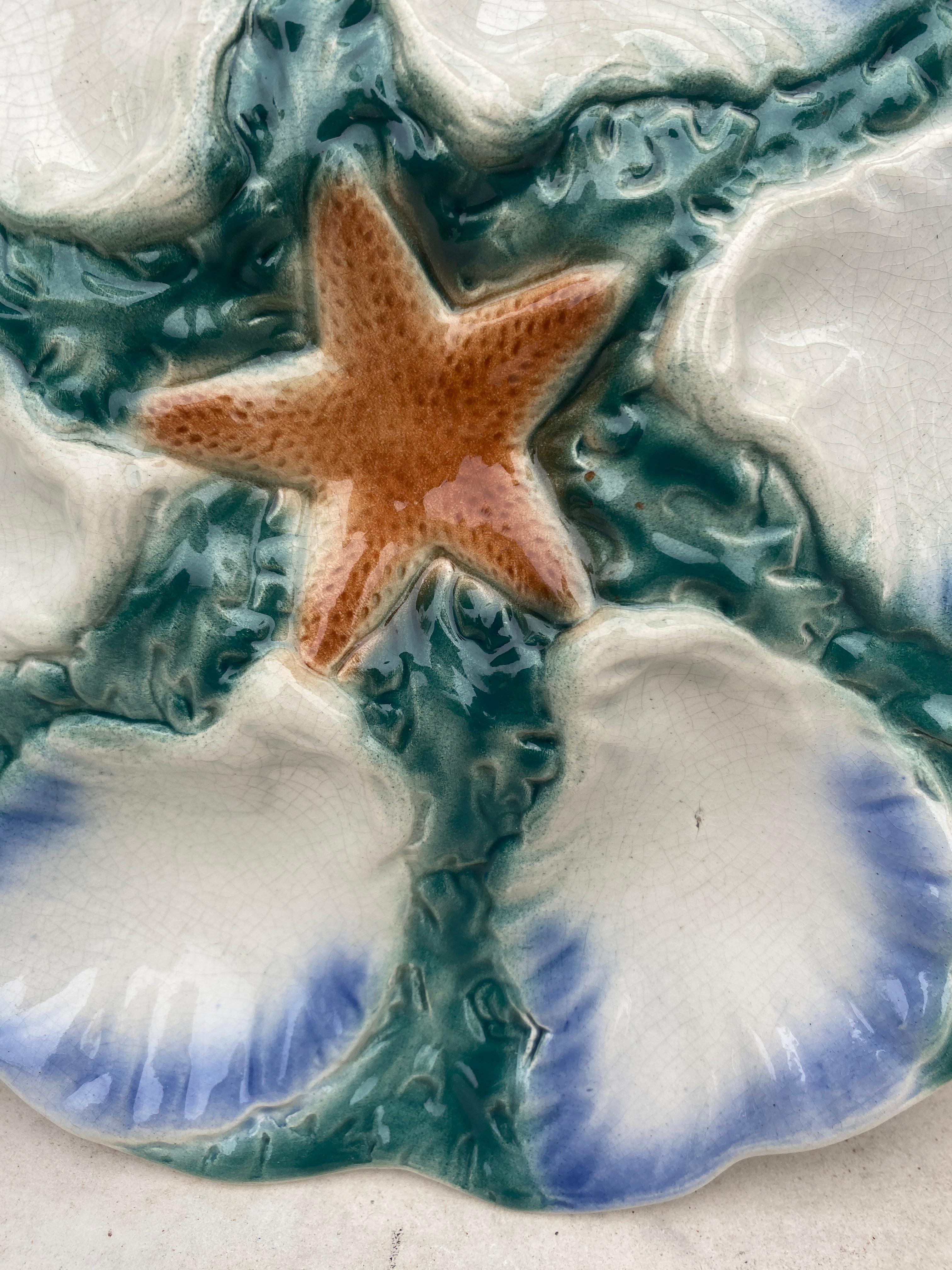 Majolica plate with orange starfish with six wells blue and white surrounded by green seaweeds Digoin ( East of France ), circa 1900.