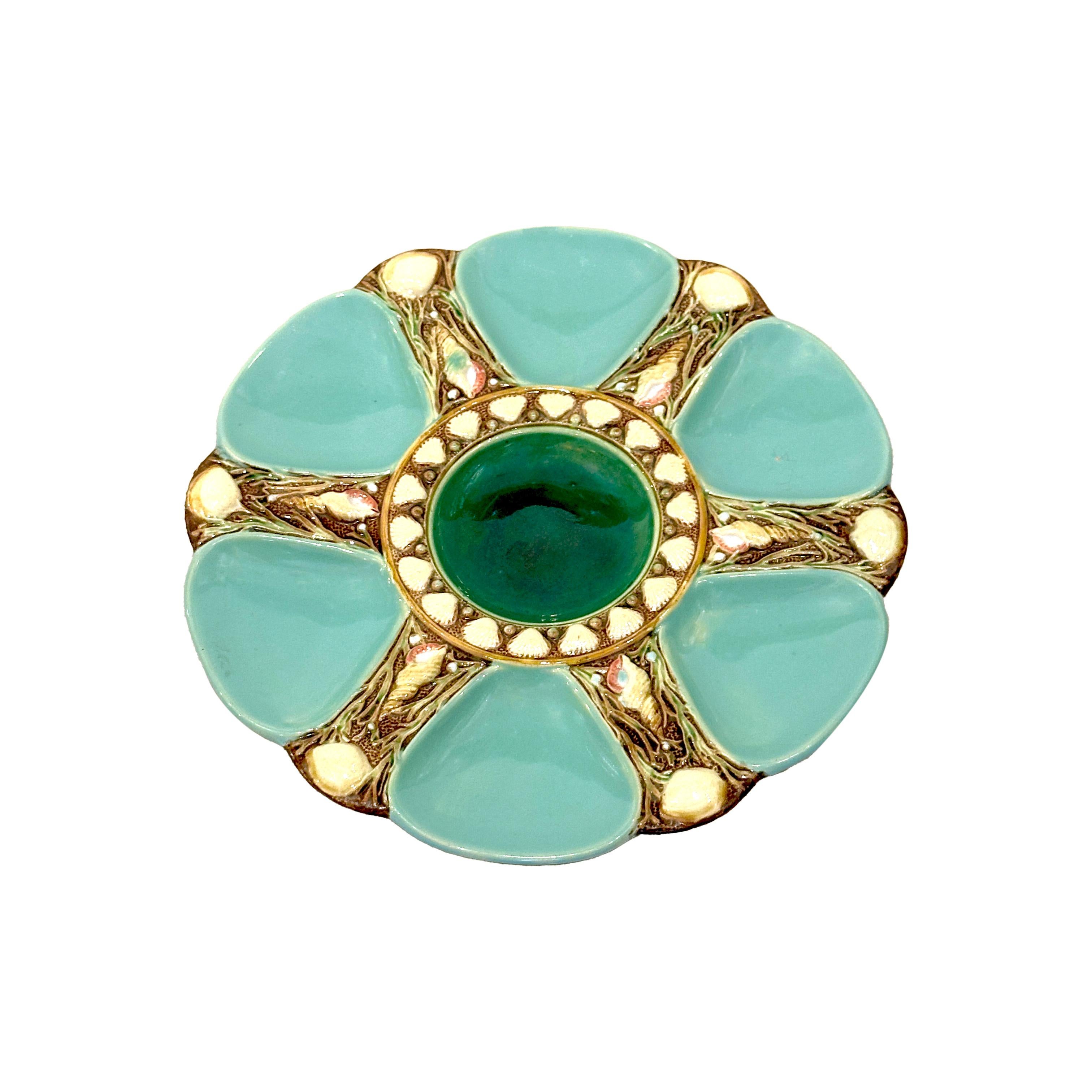 Majolica oyster plate by the English manufactory Minton. Lovely turquoise color with iridescent green tones on the middle of the plate. Decorated with refined shells, perfect to evoke a marine atmosphere. The plate is stamped below with the Minton