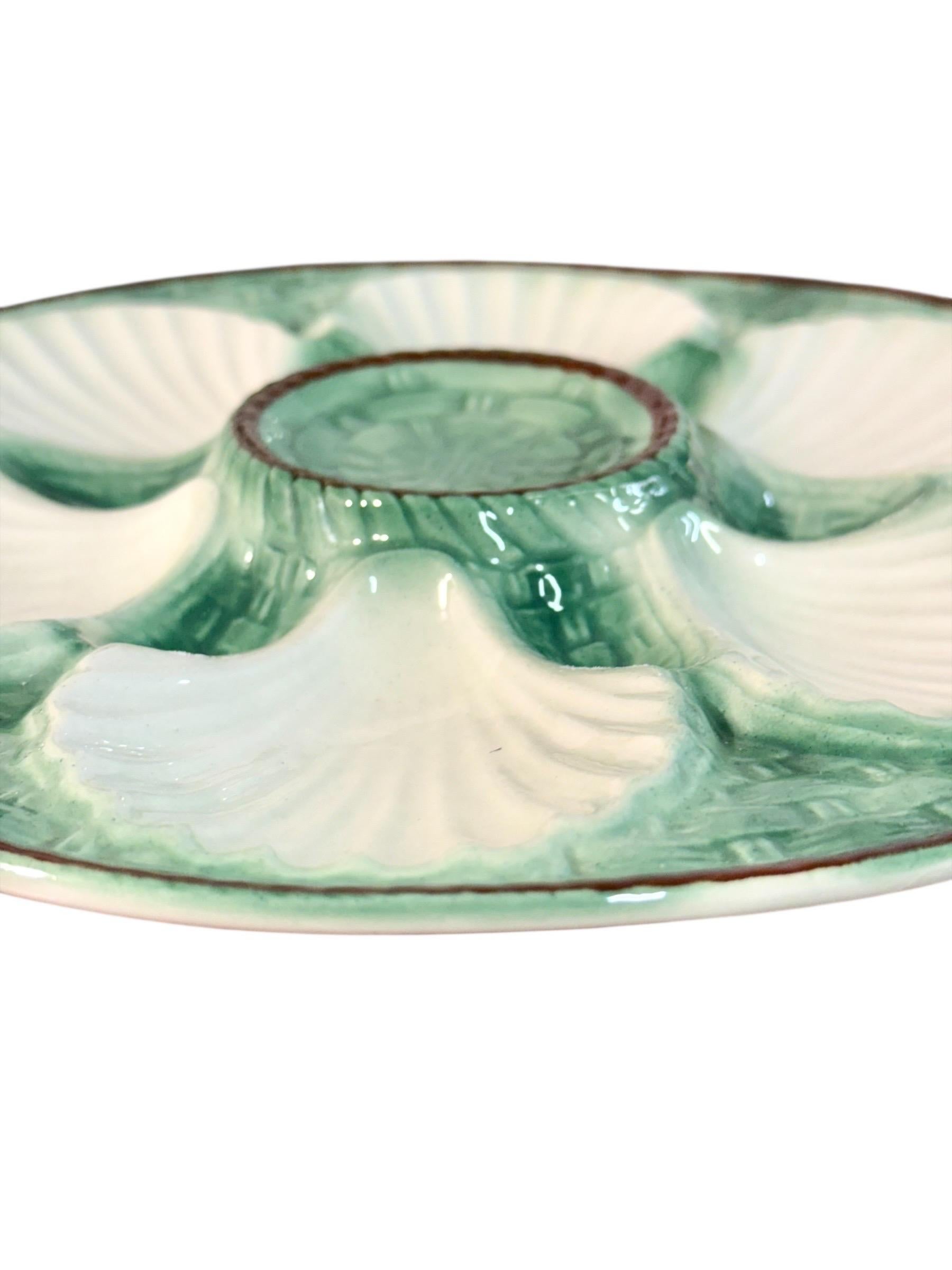 Cet impressionnant ensemble de 11 assiettes à huîtres en majolique française et son grand plat assorti, réalisés à la manière de Longchamps, date approximativement de la fin du XIXe siècle ou du début du XXe siècle. Caractérisé par un délicat fond