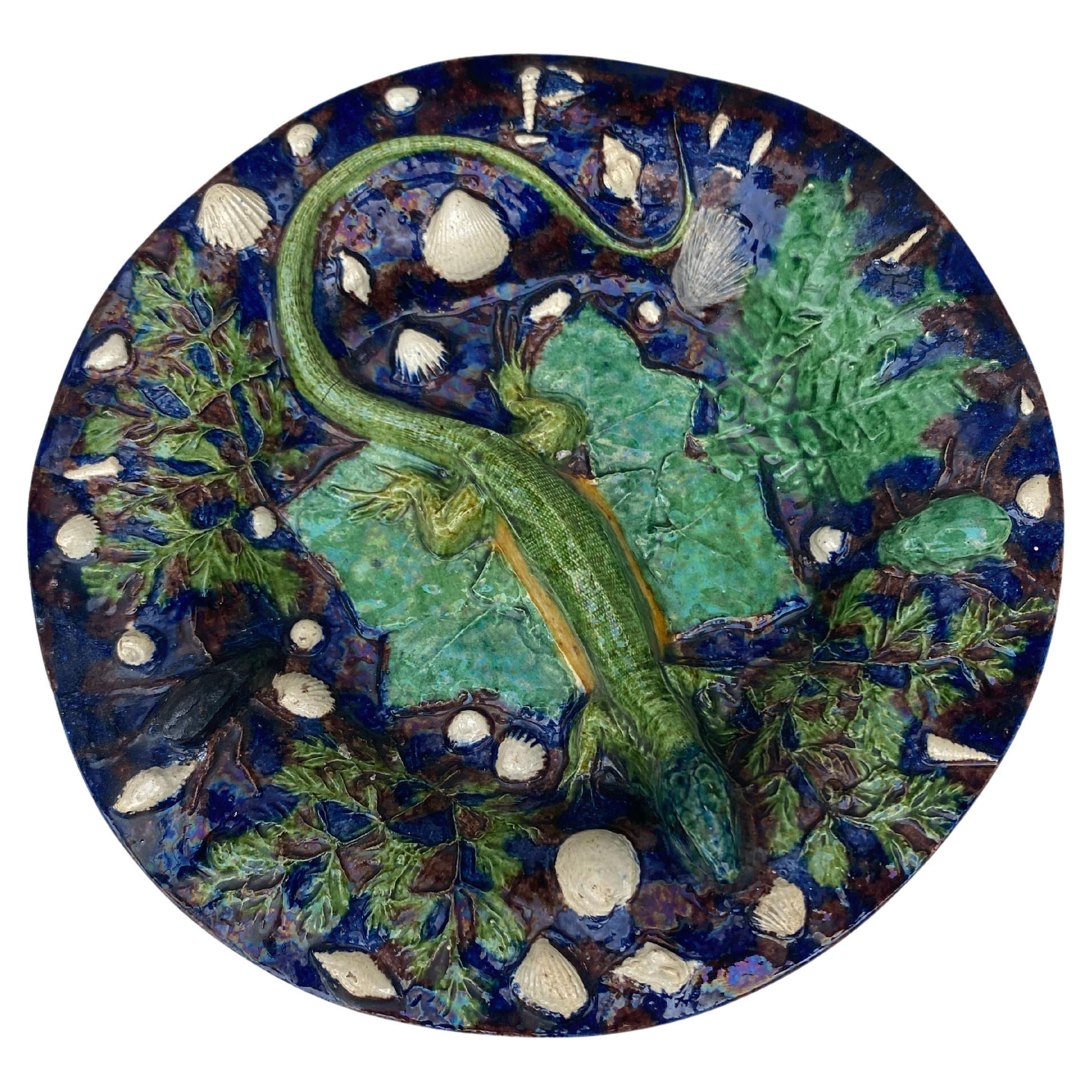 Palissy footed platter on a blue brown mottled background with a large lizard on the centre, on the platter severals white shells and different leaves attributed to Georges Pull.
The School of Paris is composed by makers as Victor Barbizet,