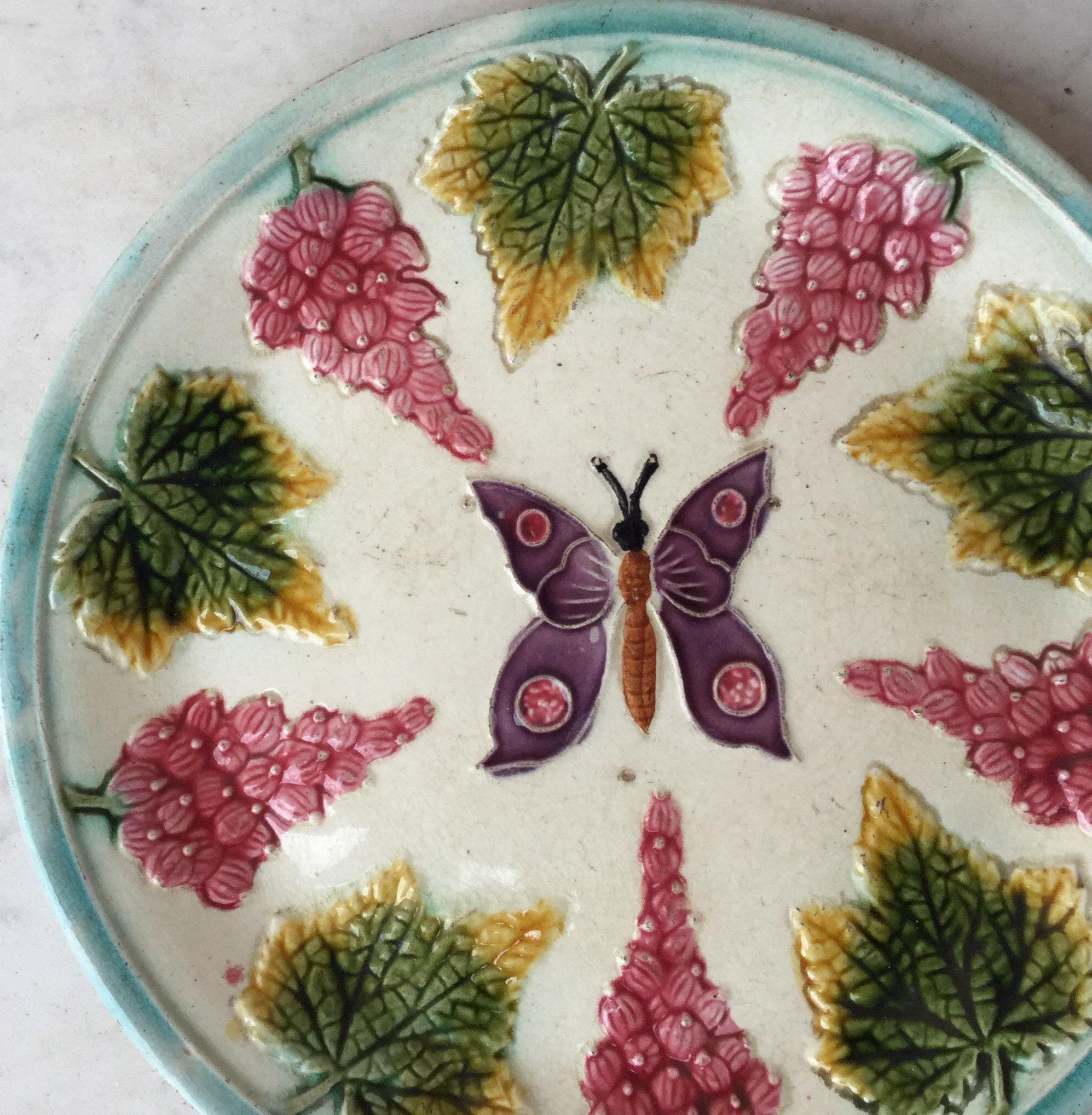 French Majolica plate with a purple butterfly on the centre surrounded by fruits, circa 1890.