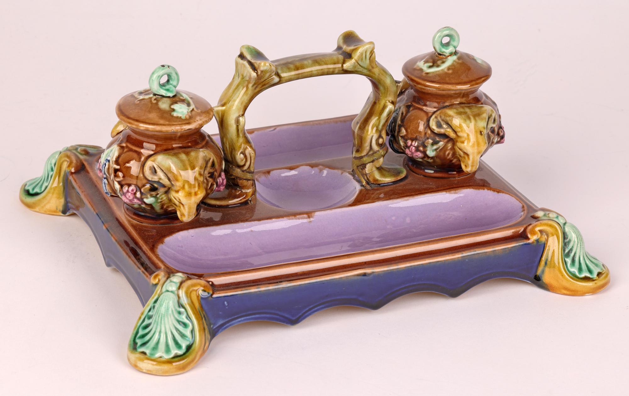 A very stylish English majolica pottery partners desk stand with inkwells with ram heads by renowned maker William Brownfield and dating from around 1870. The rectangular shaped desk stand sits raised on four scallop shell molded feet with a central