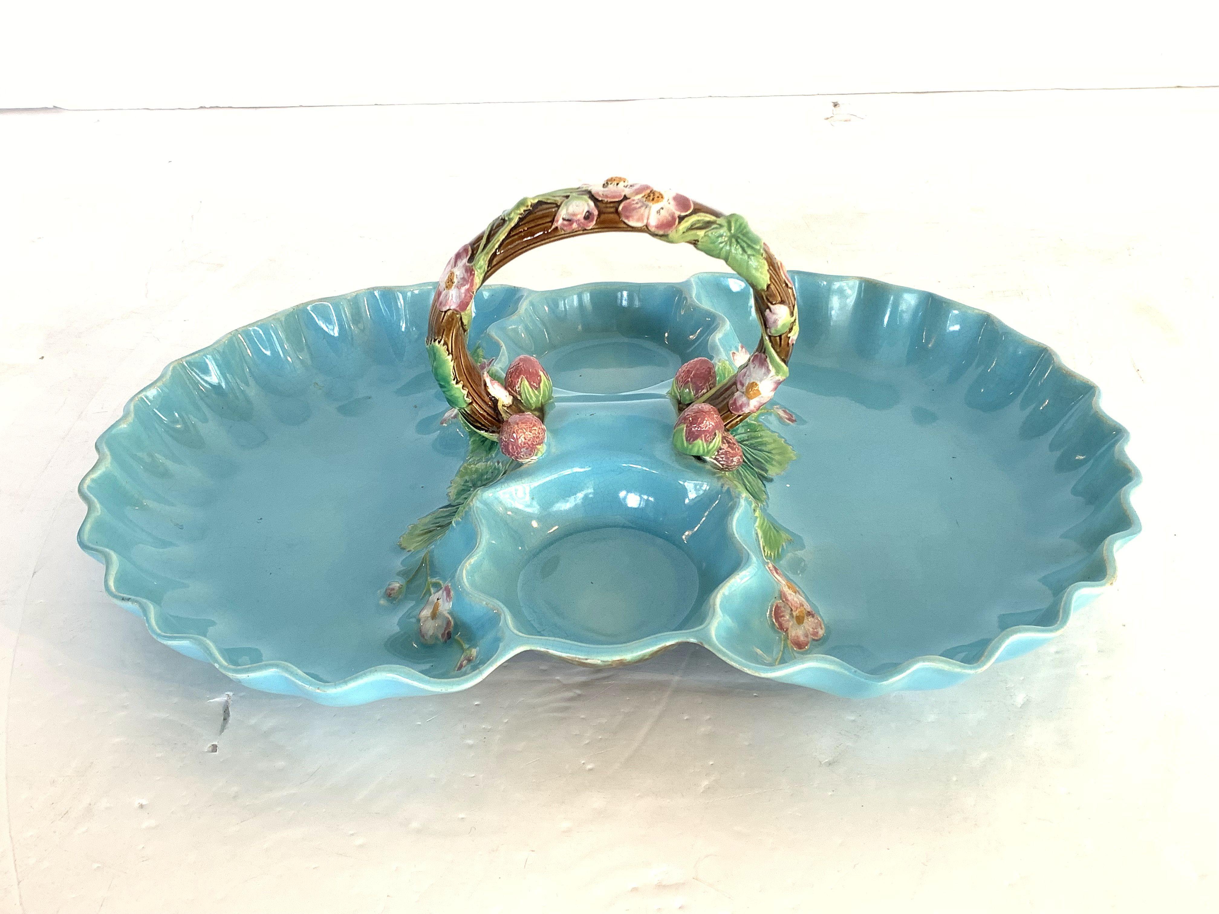 A fine Majolica strawberry server from the 19th century, by the celebrated English pottery firm, George Jones, featuring a lovely robin's egg blue exterior on an ovoid body, with a garland design handle of strawberry leaves and strawberries in green