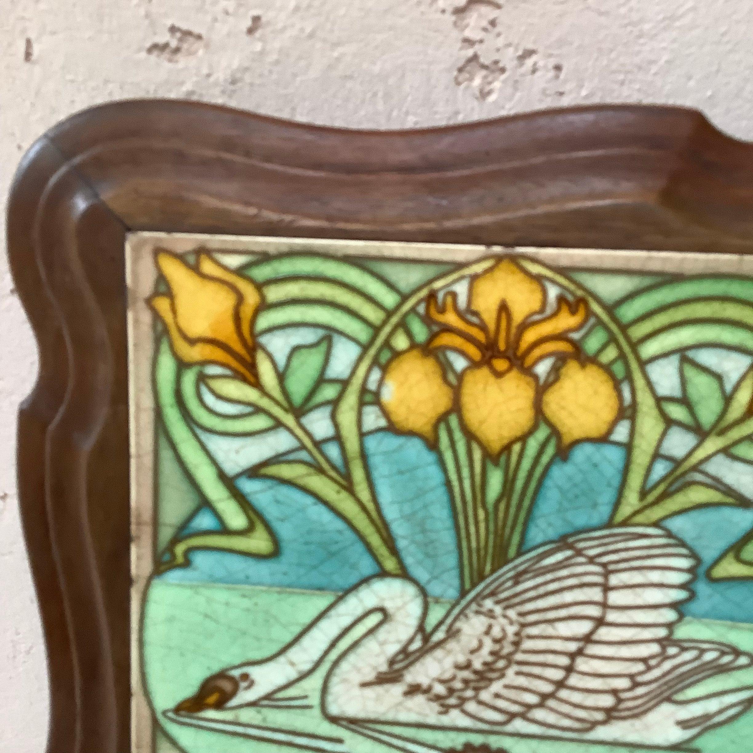 Art Nouveau Majolica swan and yellow iris trivet inset in a footed wood frame, circa 1900.