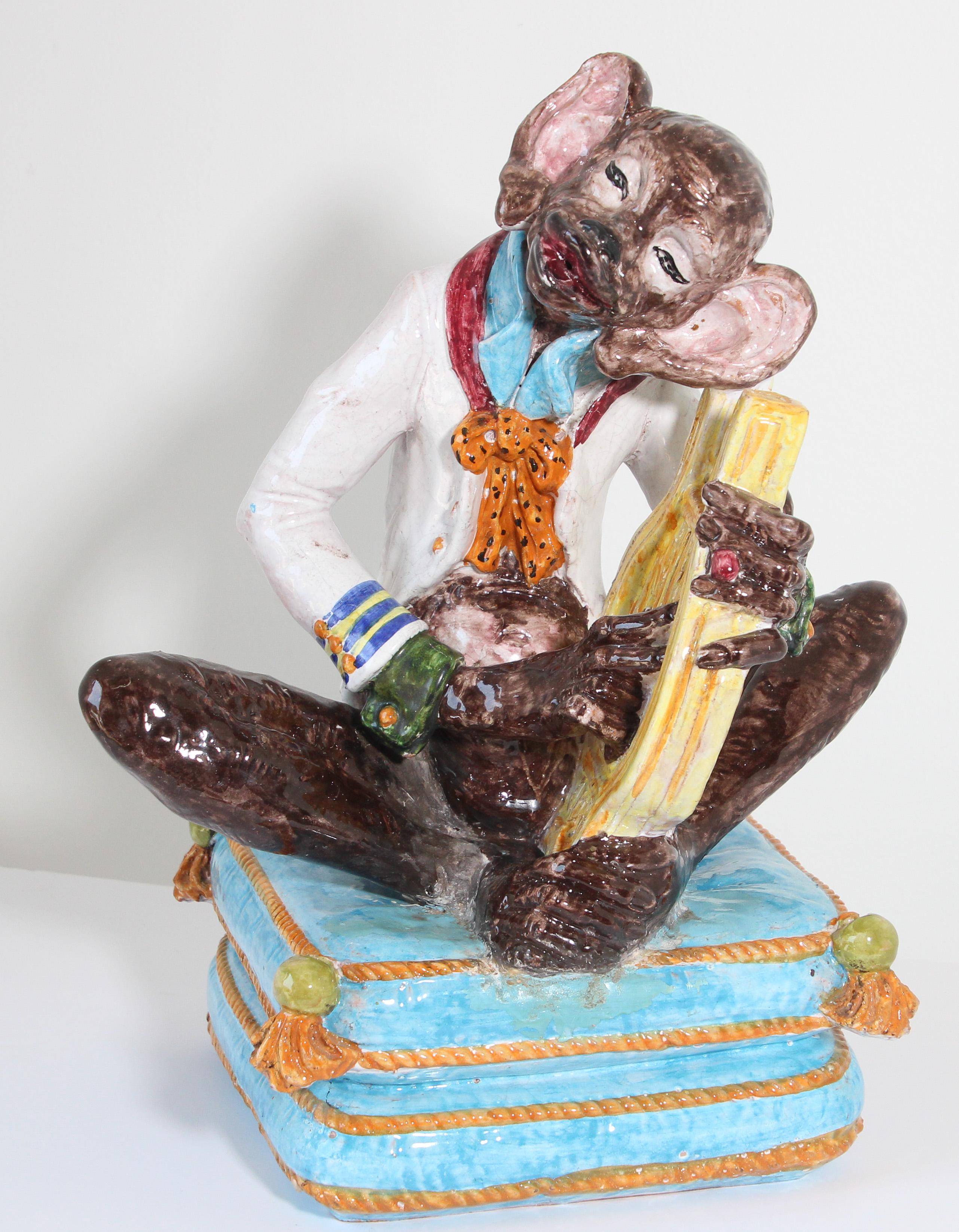 Large Enchanting French Victorian style multicolored Majolica terra cotta figure of a monkey sculpture dressed up playing the harp seated on a double turquoise tasselled floor pillows with beautiful detail throughout.
Heavy pottery with gloss