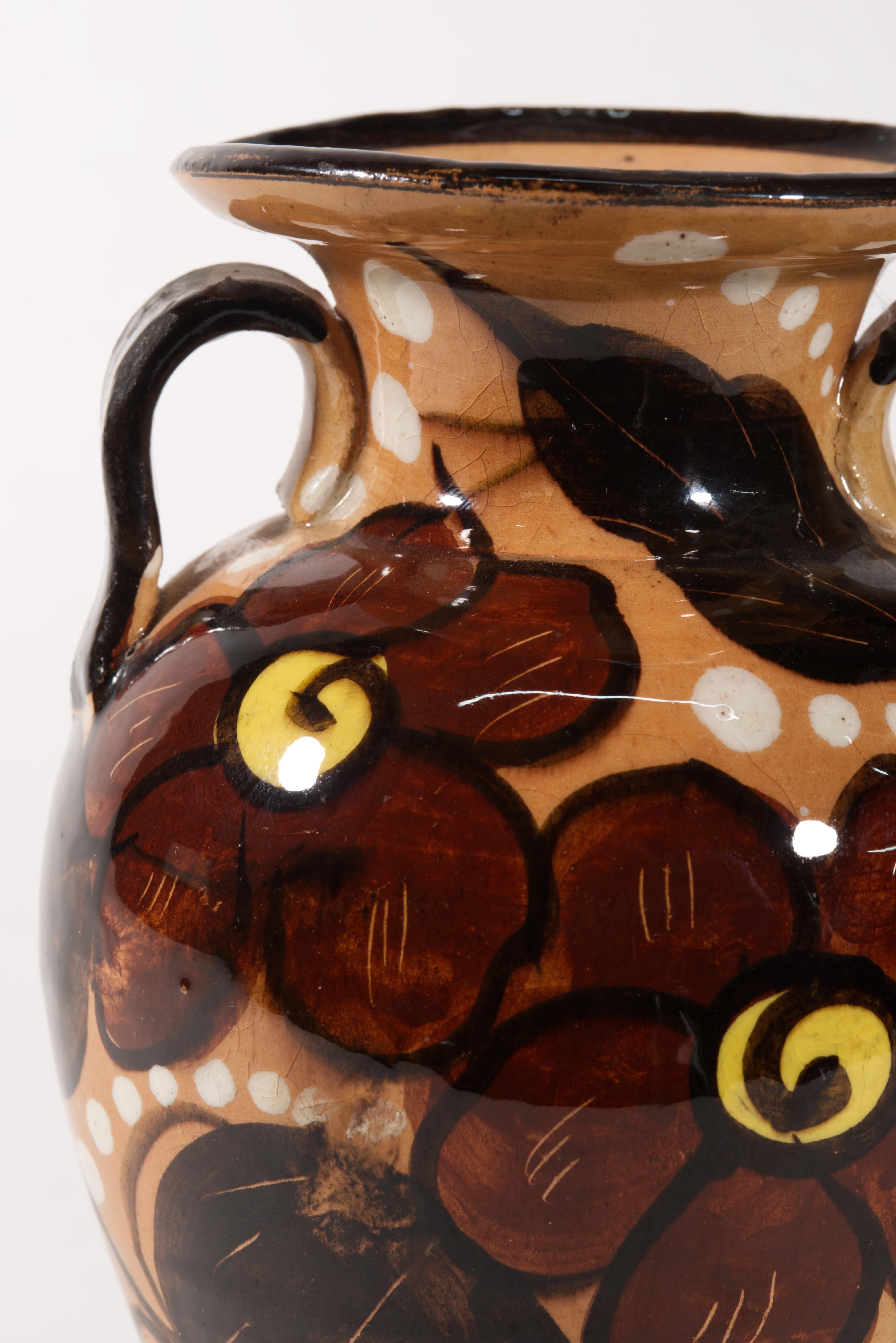 Vintage pottery vase features urn shaped body with twin handles framing the wide rim, decorated with majolica glaze in organic, earthy brown palette. The abstract floral decor is very similar in style to pieces that were designed for Bitossi by Aldo