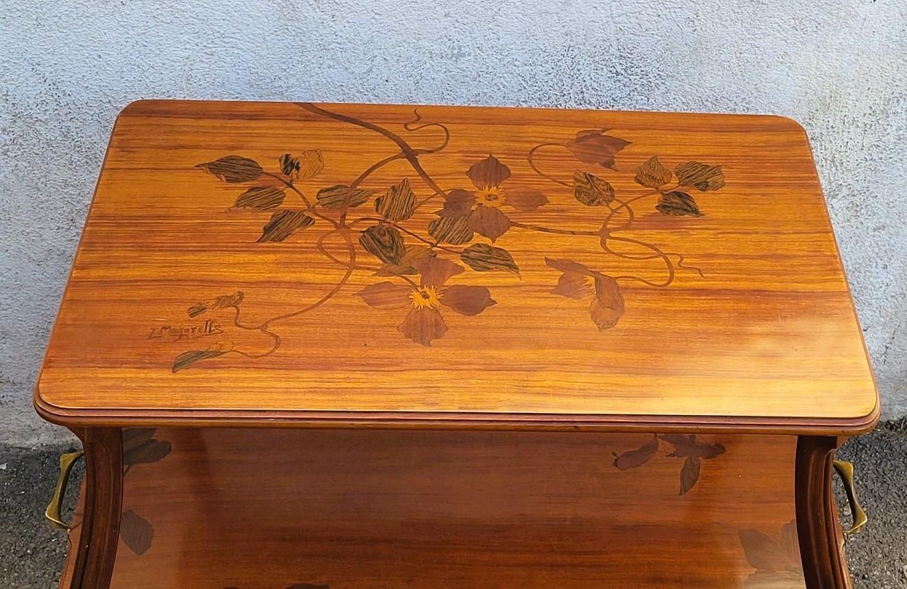 Tea table with 2 trays, in marquetry of different exotic wood species: the trays are decorated with flowers (clematis) and leaves, the upper tray is signed L Majorelle.

It is also decorated with 2 bronze handles

Good general condition, small chips