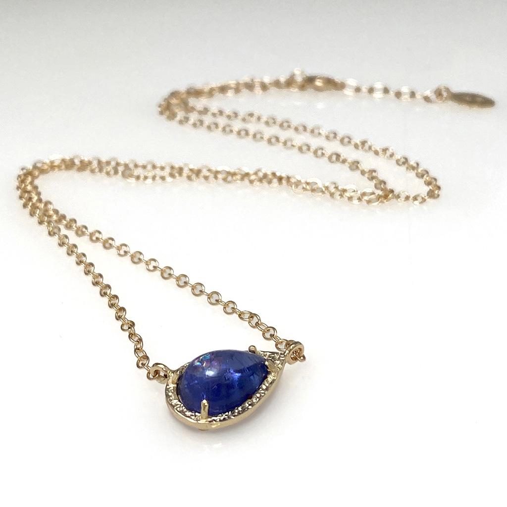 Keiko Mkta's lovely Majorelle Necklace is handmade from a rich blue pear-shaped Tanzanite (2.91 Carats) set in a textured 14 Karat Yellow Gold frame. The beautiful Tanzanite rests diagonally on the neck creating a unique look. The contemporary