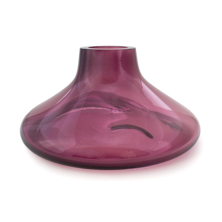 Makemake Purple Iridescent L Vase + Bowl by ELOA
Material: Glass
Dimensions: D40 x W40 x H25 cm
Also Available in different colours and dimensions.

Makemake is reminiscent of Jupiter‘s ring. The object was designed with a double functionality
