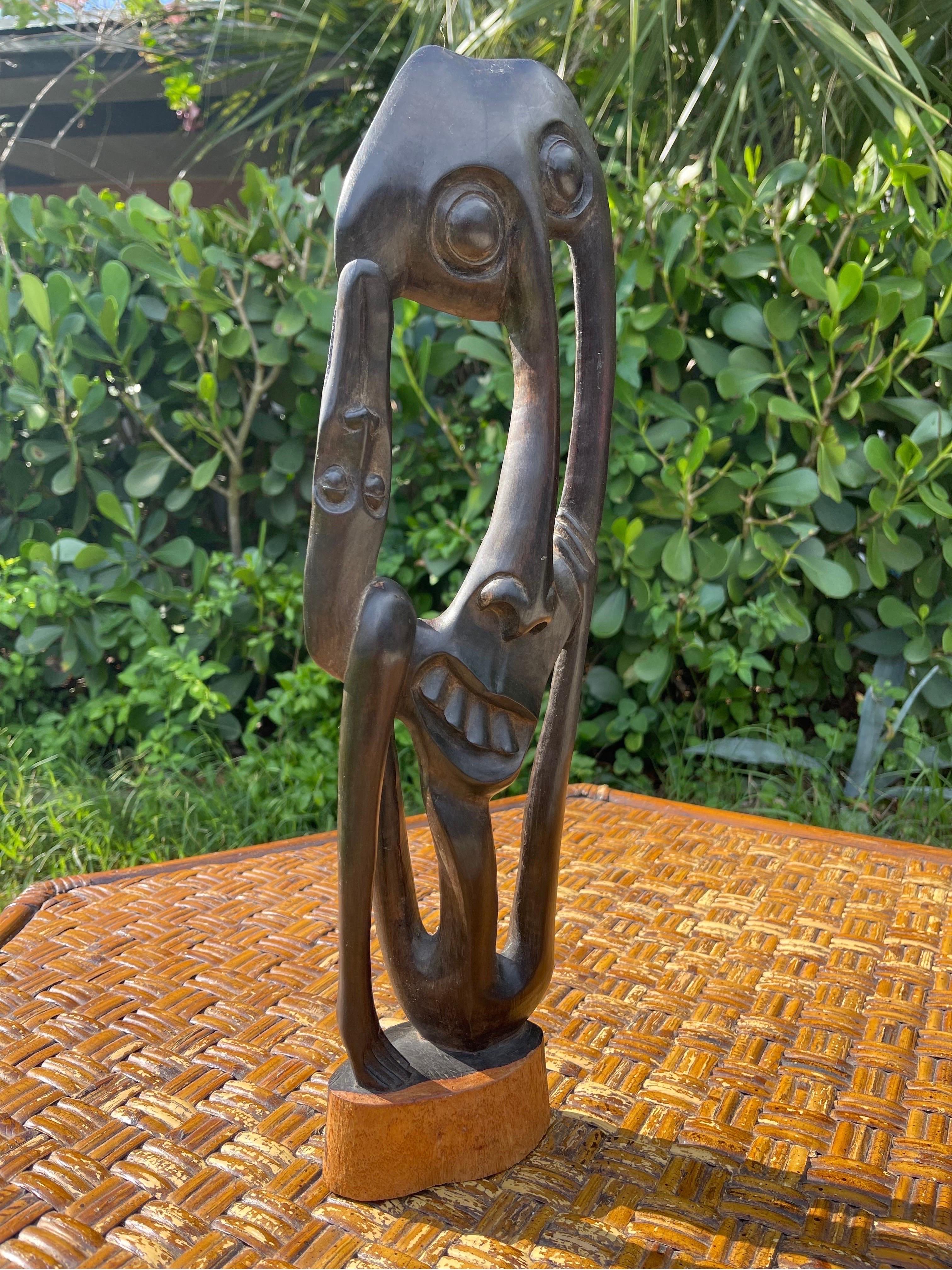 A whimsical sculpture of multiple abstract faces. Carved of one piece of solid ebony.