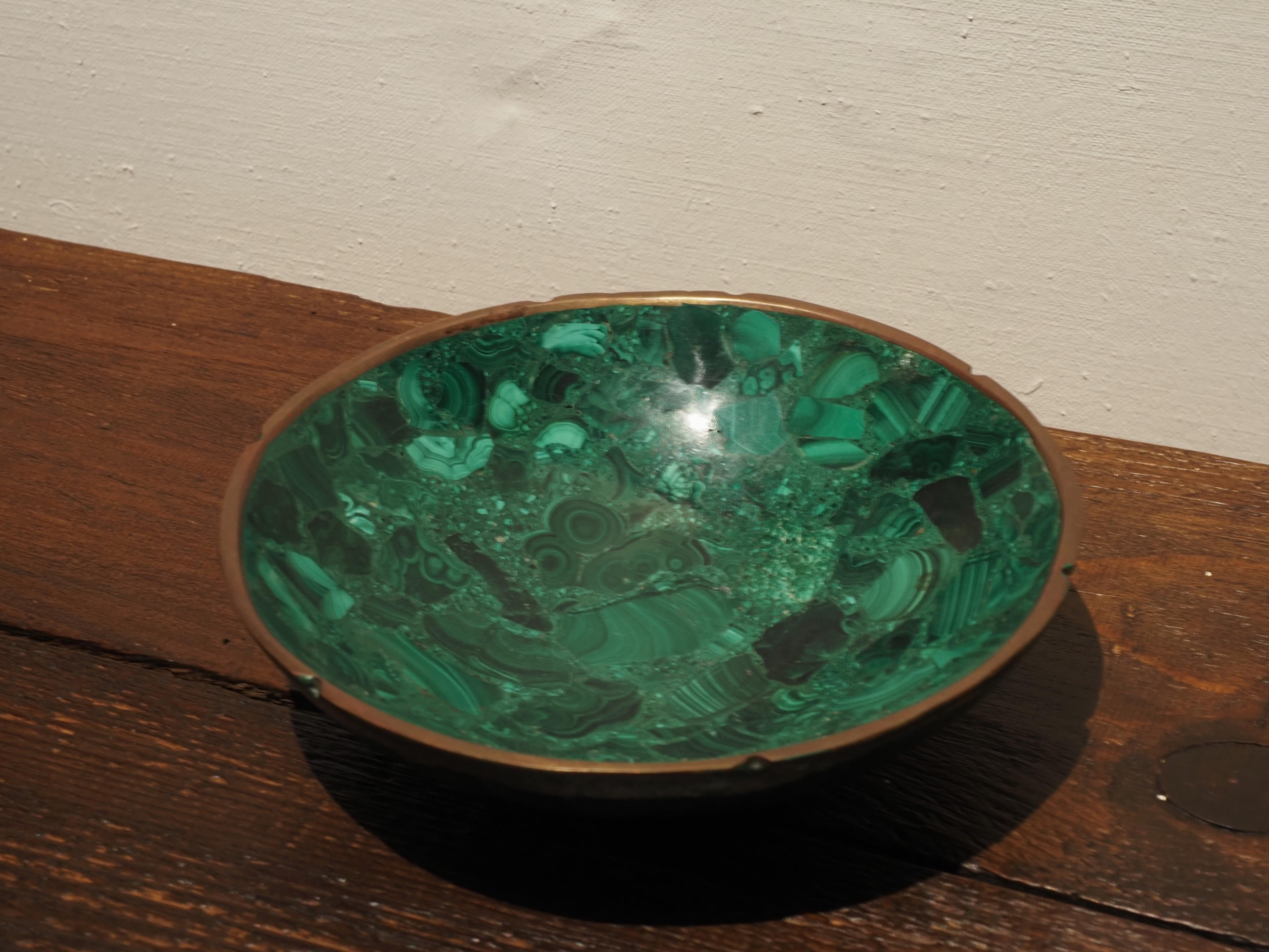 Vassoio ovale in malachite con bordo in ottone. La ciotola videpoche vintage è decorata con cerchi dorati sagomati. Le ricche tonalità smeraldo esaltate dagli accenti dorati aggiungono un tocco di lusso a qualsiasi casa.
In ottime condizioni, senza