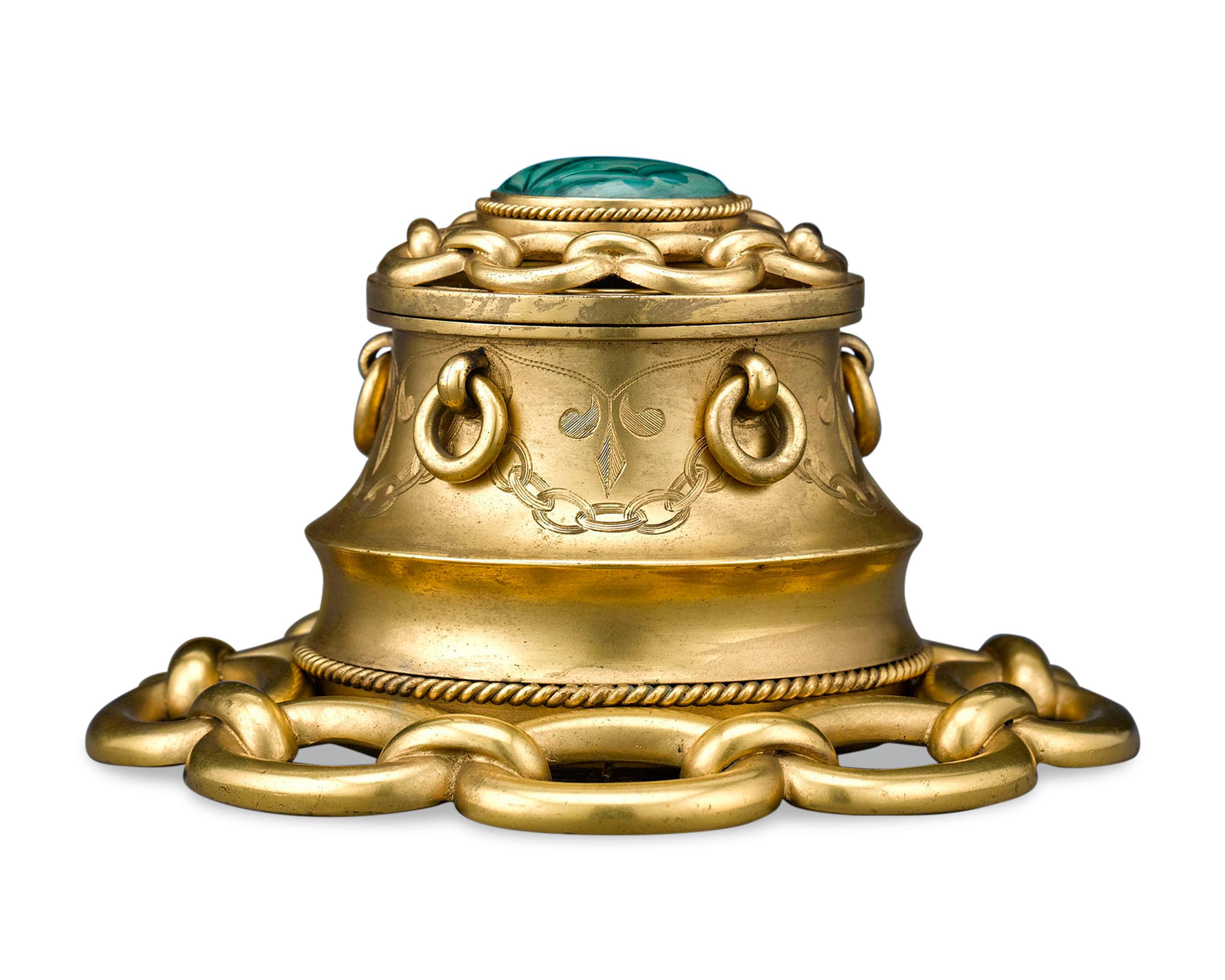 A large malachite cabochon is inset atop this turn-of-the-century inkwell. The vivid green mineral provides a wonderful contrast to the doré bronze body, which is crafted in a linked chain motif. This fine antique desk accessory retains its original
