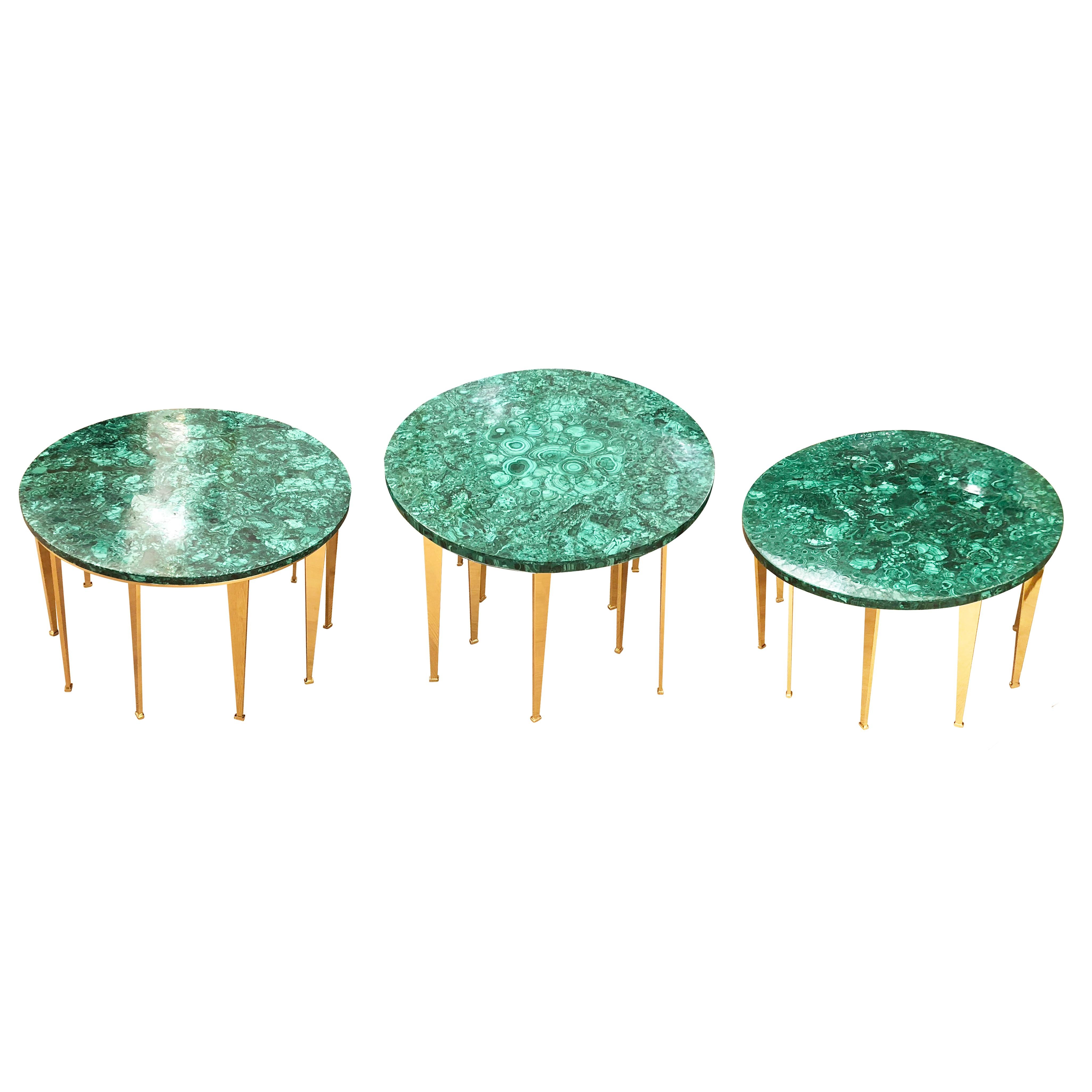 Versatile set of limited edition tables that can be used together to form a coffee table or individually as side tables. Each has a malachite top and a brass base consisting of several tapering legs angled in different directions. The taller center