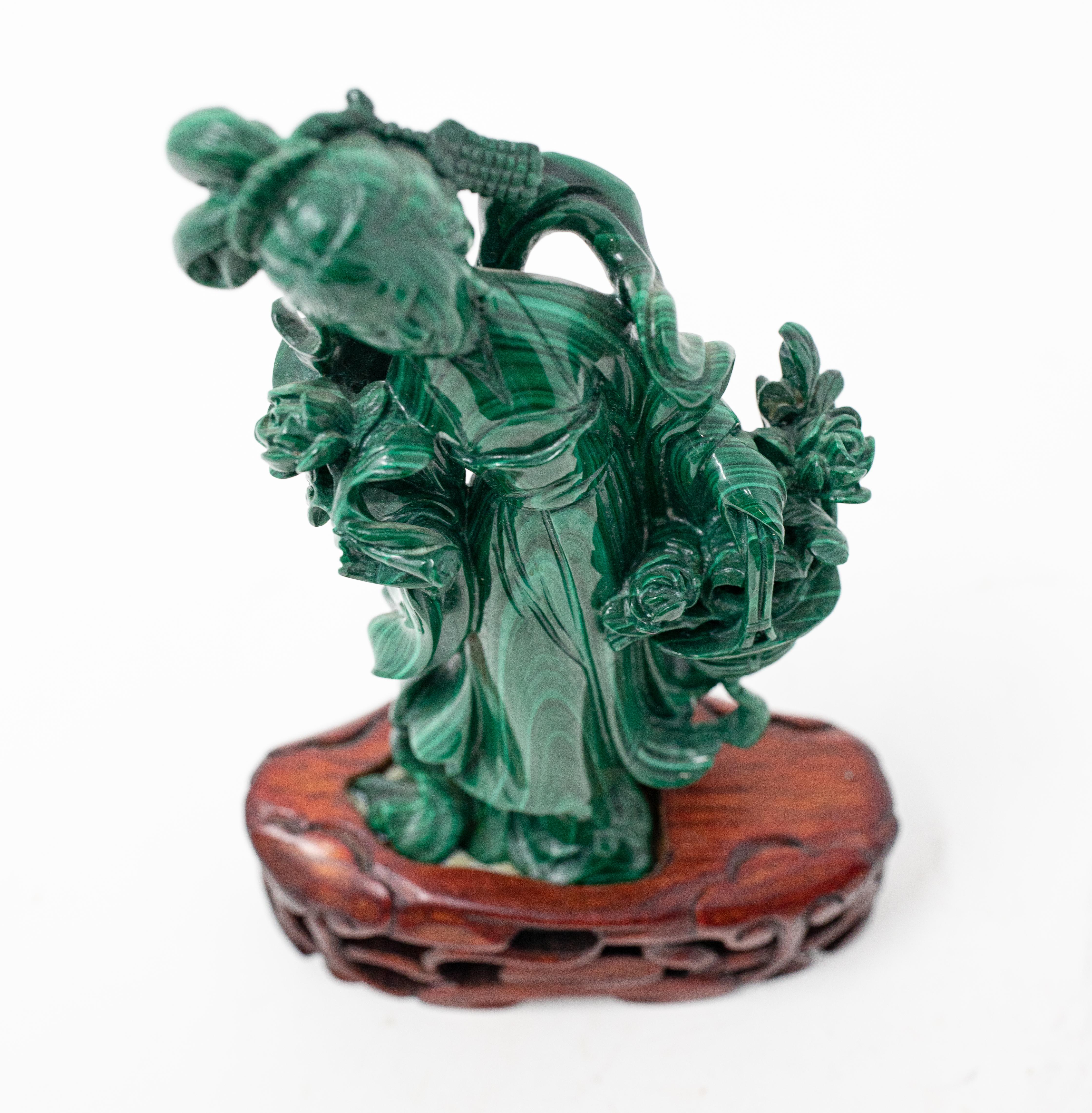 Offering the magnificent hand carved He Xiangu malachite statue on a rosewood base. Starting at the beautiful rosewood base it has open scrollwork and puffs. The He Xiangu is done gorgeously and all the natural striations were followed to make her