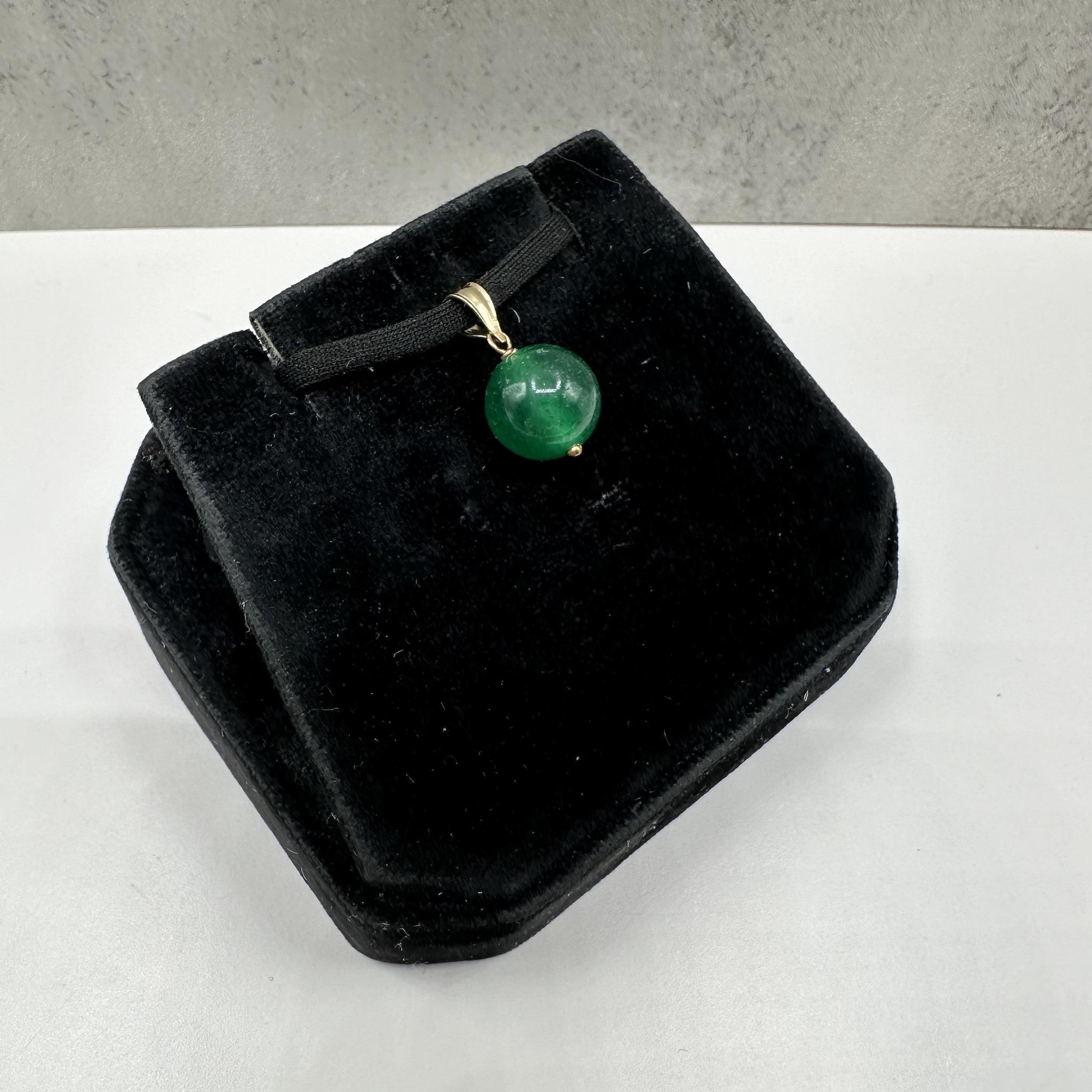 Cet élégant pendentif en malachite en or jaune 14kt est orné d'une riche pierre de malachite ronde de 10 mm qui met en valeur ses bandes vertes caractéristiques et sa beauté naturelle. La lunette en or jaune poli crée un contraste chaleureux qui met