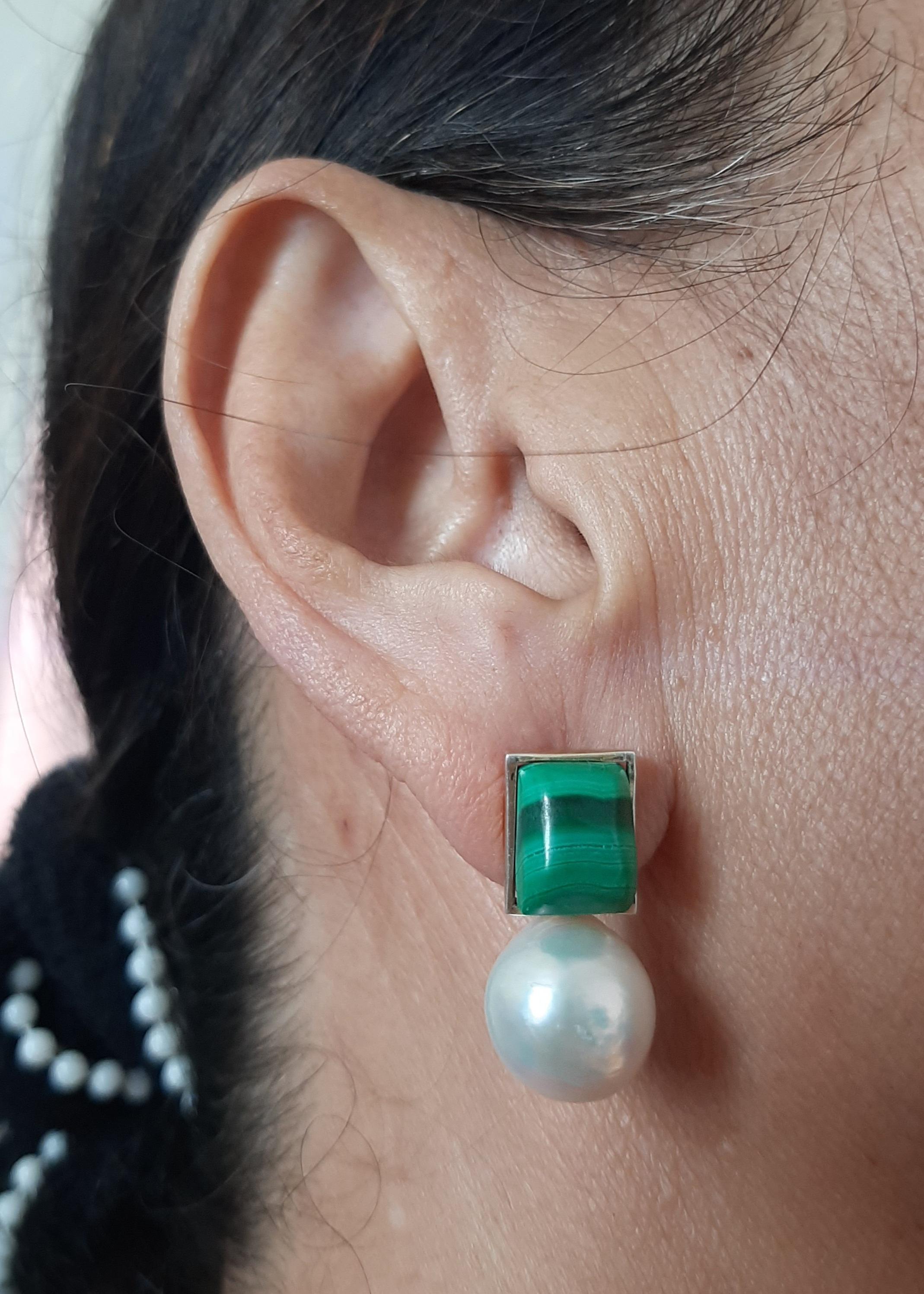 Questi semplici ma eleganti orecchini fatti a mano hanno 2 cabine rettangolari di malachite 8x10 mm incastonate in un castone in oro giallo 14 Kt alla cui sommità sono sospese 2 perle barocche bianche di 13 mm di diametro.

Nel 1978 il nostro