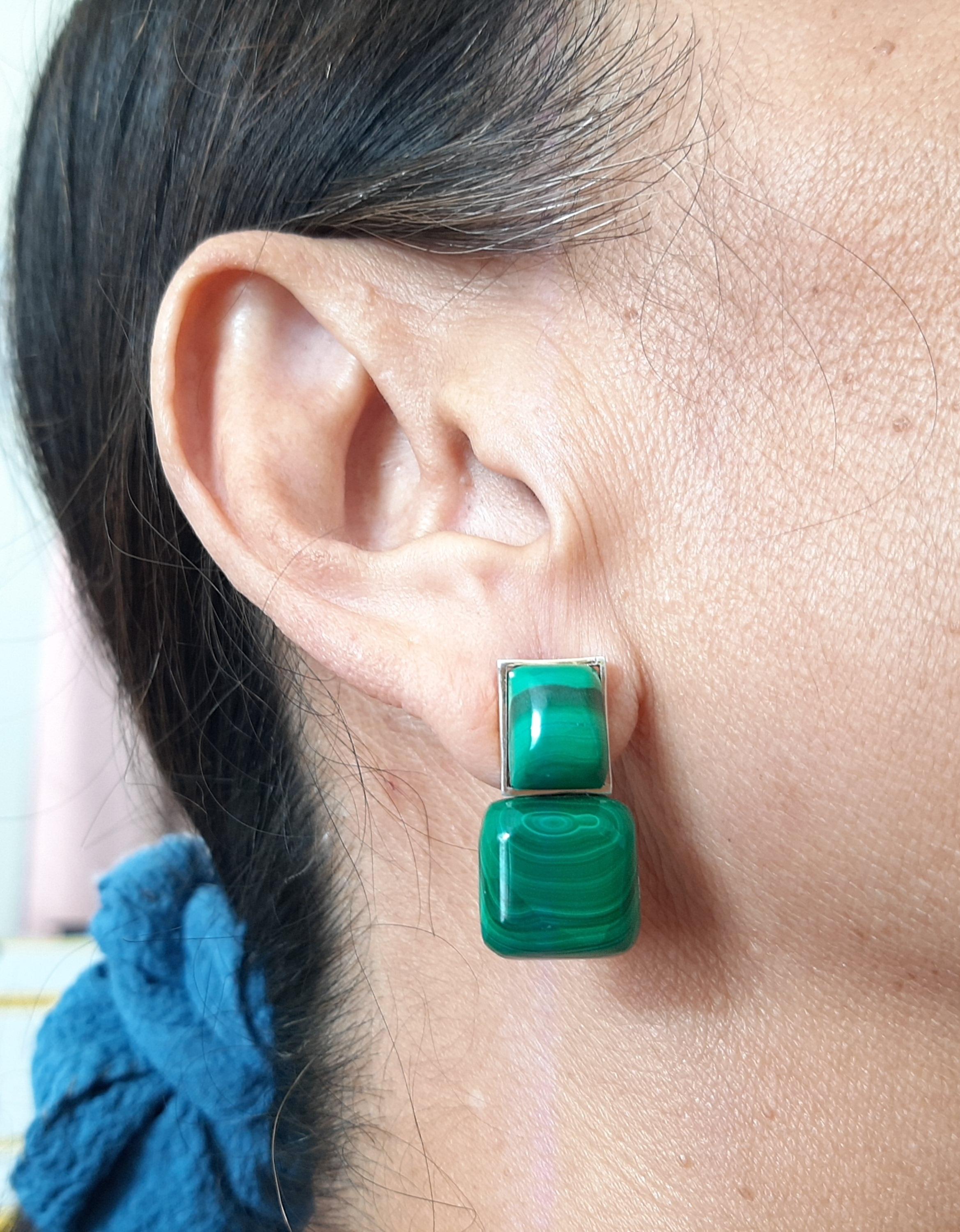 Questi semplici ma eleganti orecchini fatti a mano hanno 2 cabine rettangolari di malachite di 8x10 mm incastonate in un castone in oro giallo 14 Kt alla cui sommità sono sospese 2 malachiti a forma di cuscino di 14x14 mm.

Nel 1978 il nostro