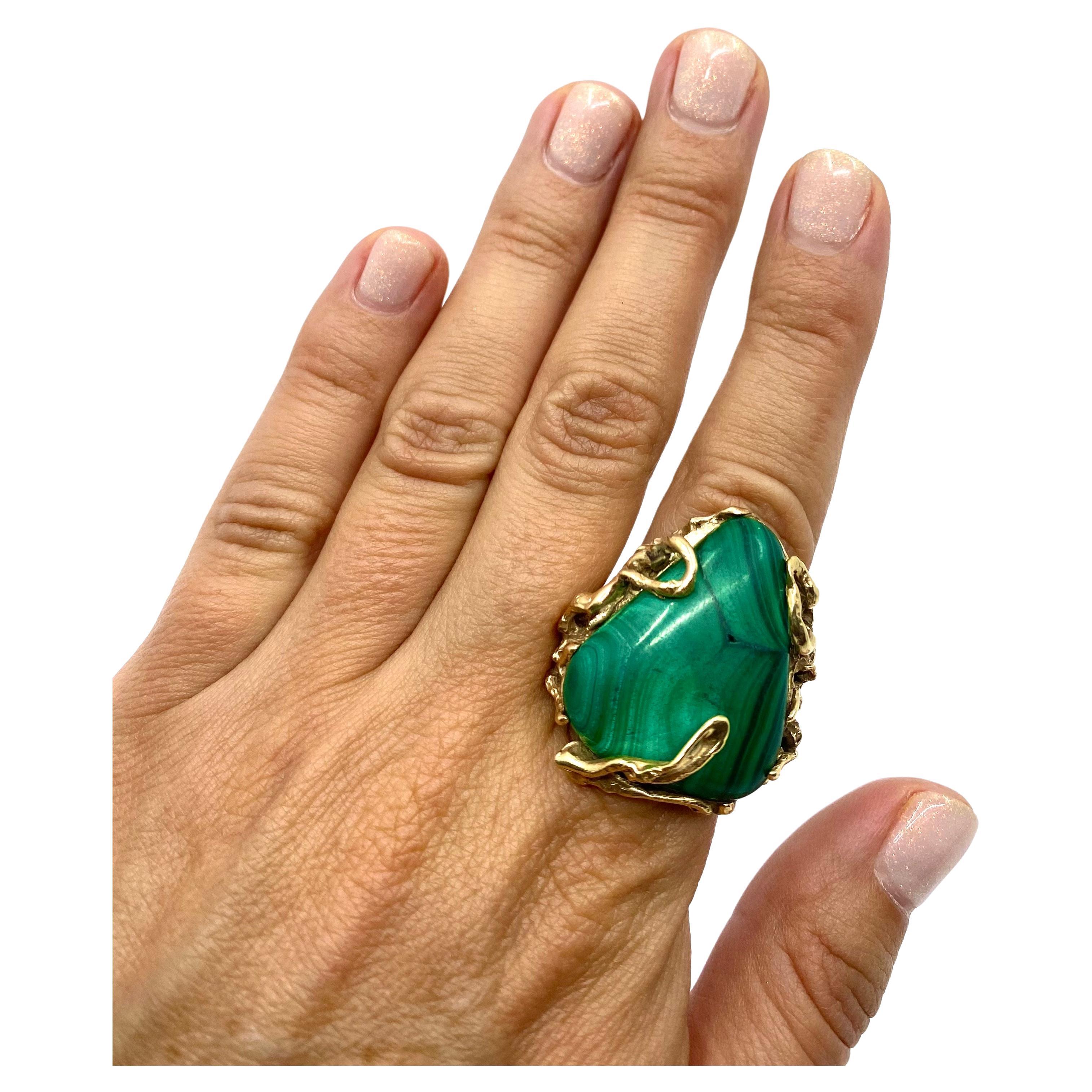 
A fascinating malachite ring, circa 1970s, made of 14k gold. The ring was artfully crafted by using the wax casting technique. A whimsical looking shank “hugs” the triangular malachite like a vine and overspills on the surface of the gem. This