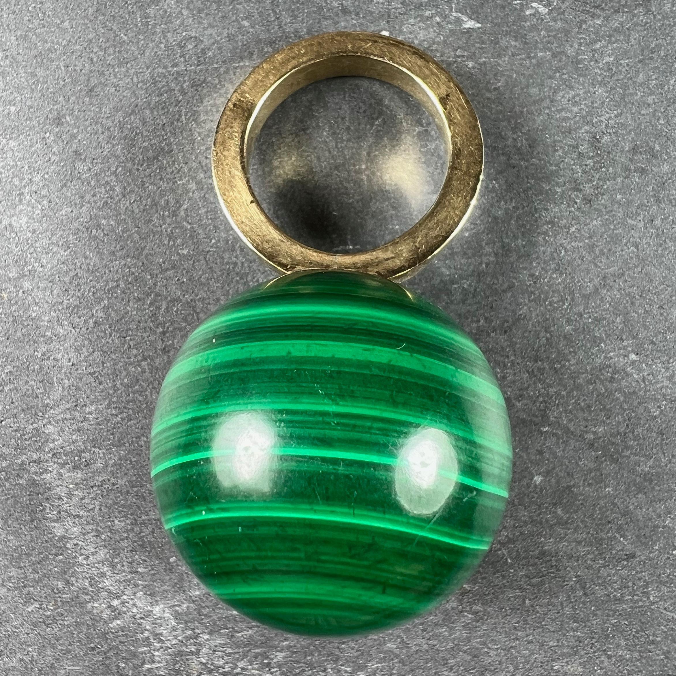 An 18 karat (18K) yellow gold ring in the funky style of the 1970s set with a large malachite sphere or ball. This unusual jewel may be worn as a pendant or a ring according to the wearer's preference. The ring is stamped with the owl mark for
